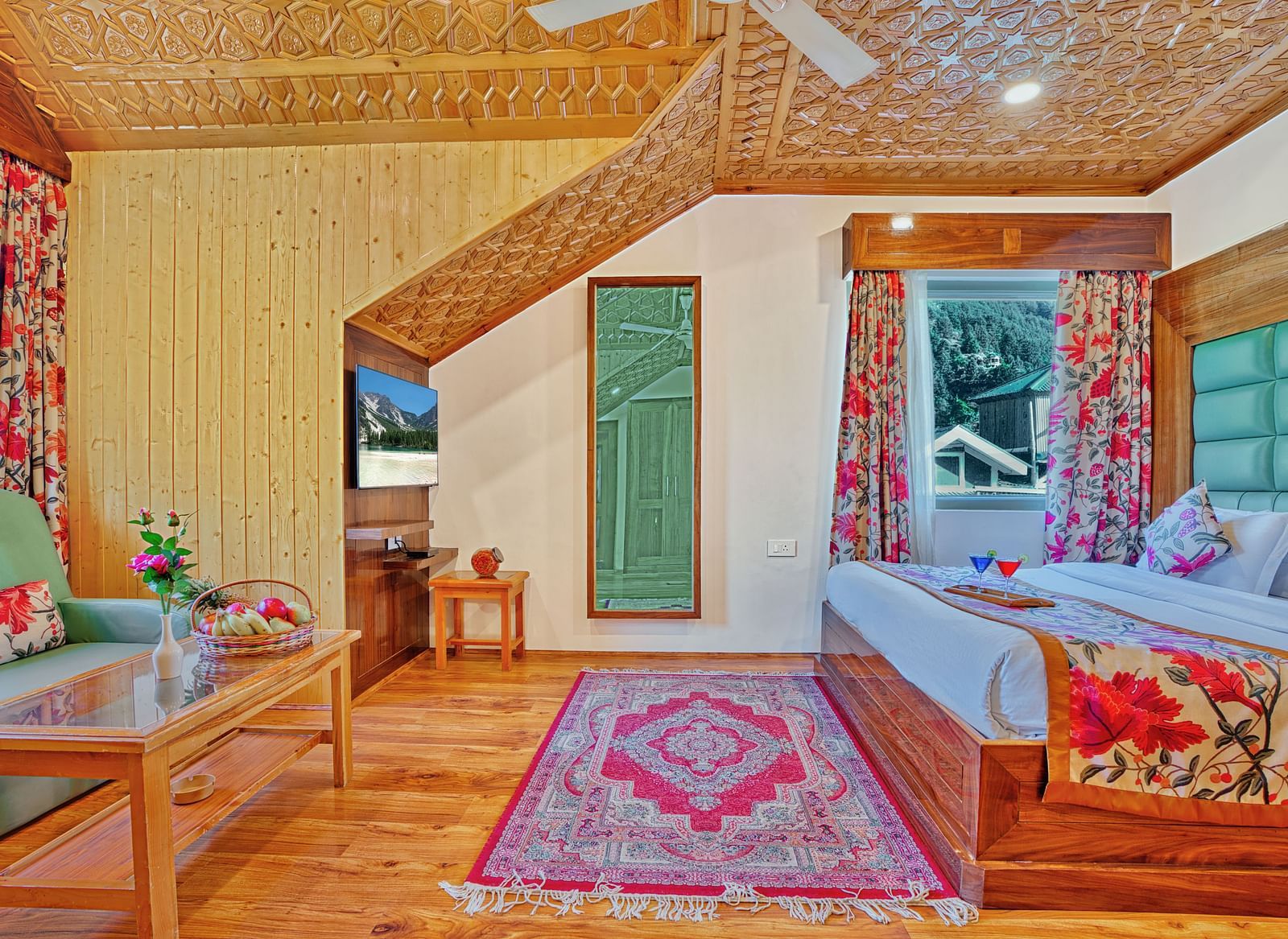 A spacious room at Royal Comfort Regency featuring a sloped wooden ceiling, floral curtains, a bed with a green headboard and a pink patterned rug.