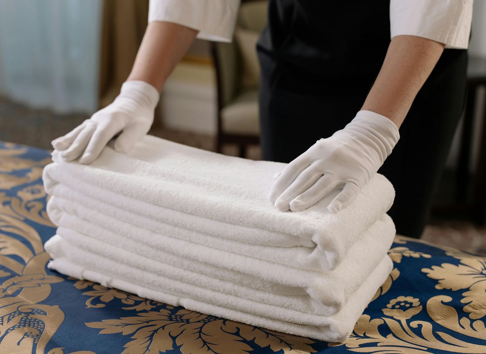 A person neatly arranging a white stack of towels.