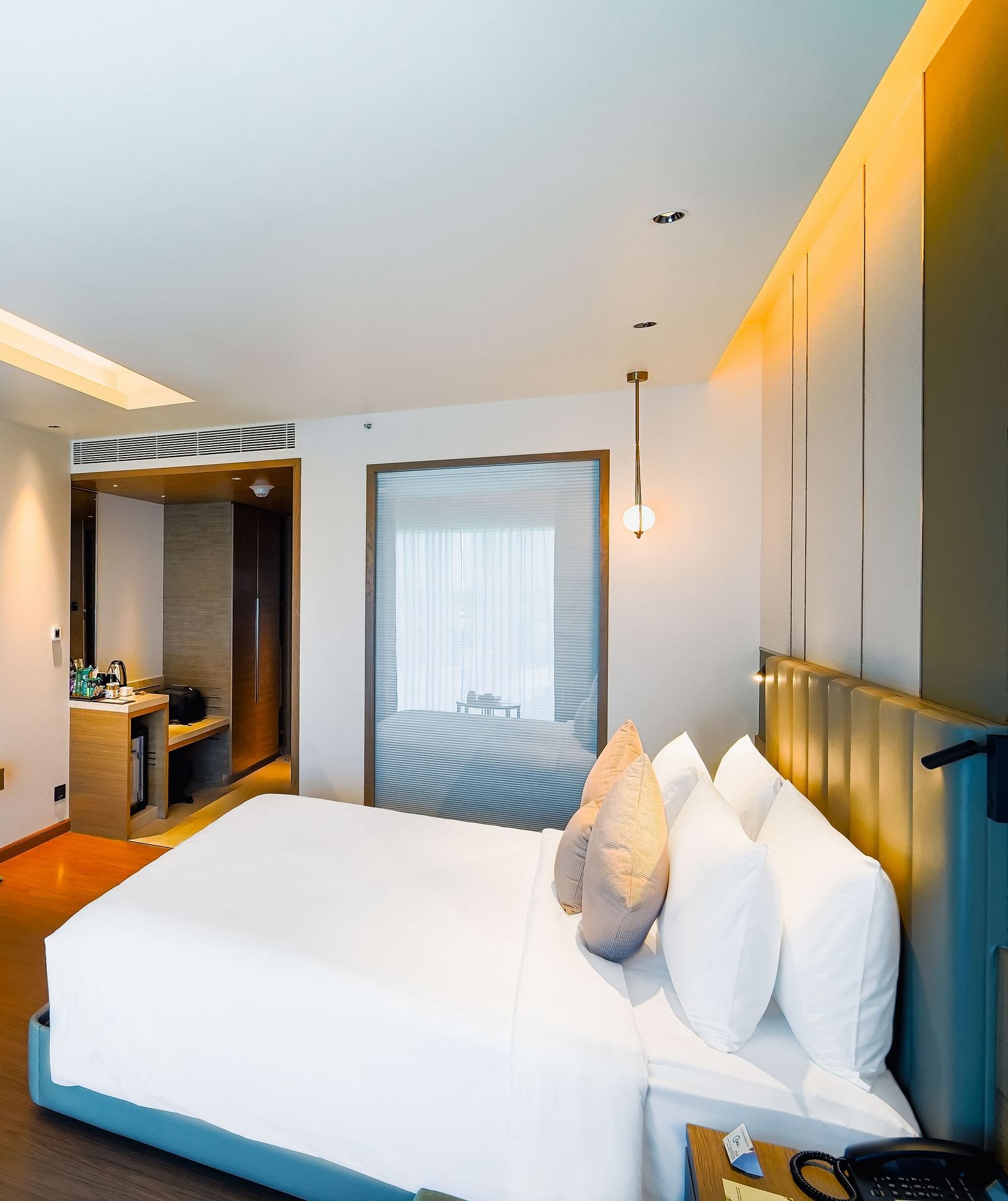 An image of a room with a large bed, work desk, and a wall-mounted television