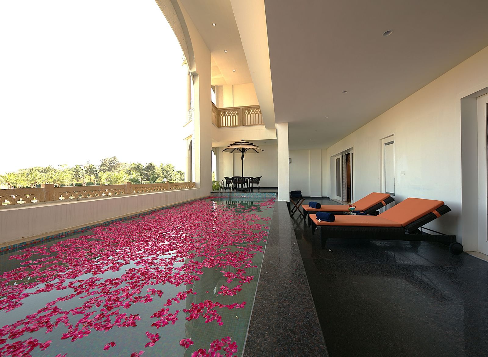 A balcony in the Premium Luxury Villa featuring a pool with rose petals, lounge chairs, and panoramic views of the hotel - Kaldan Samudhra Palace