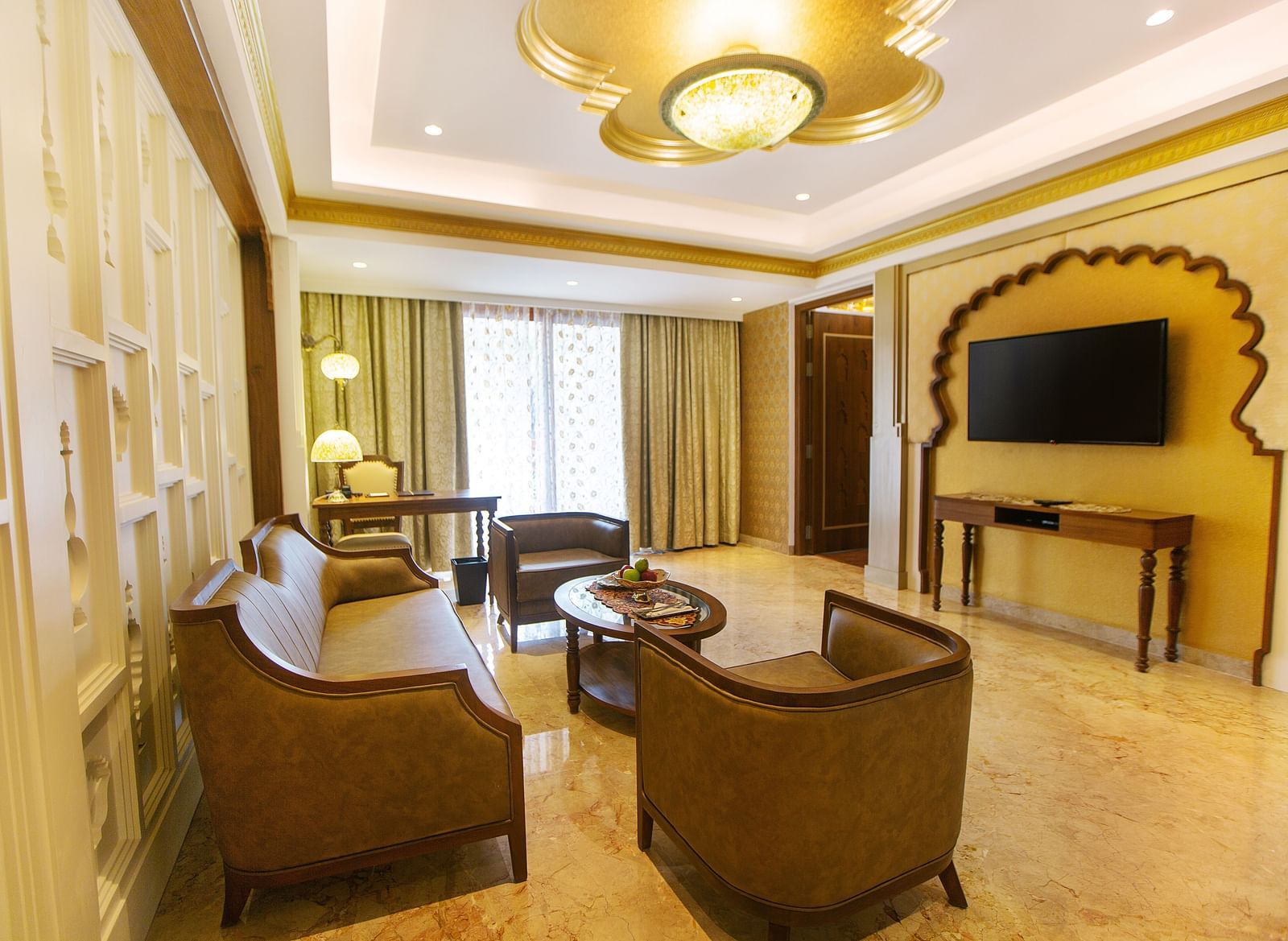 The living room of Executive Palace Suite featuring a coffee table surrounded by couches, a television, and a wall-mounted flat screen television - Kaldan Samudhra Palace