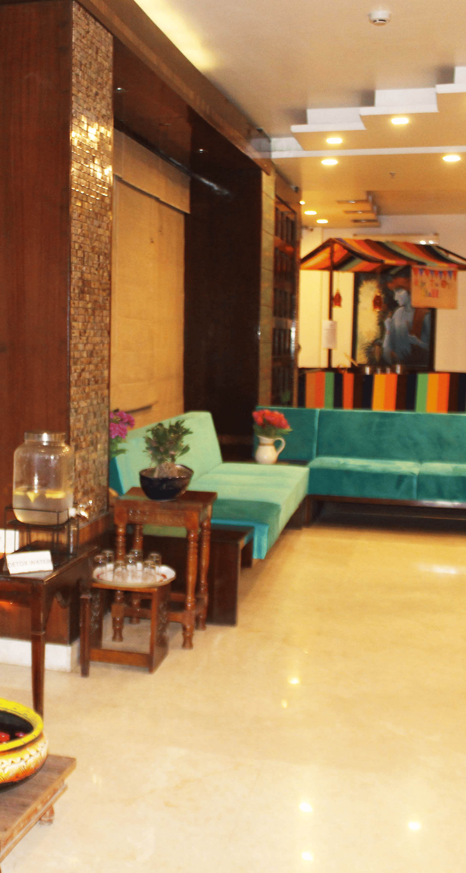 A warmly lit tiled lobby of the hotel with comfortable sofas and a painting of the lord Ganesha on the wall  - TGI Apple Inn, Jaipur 