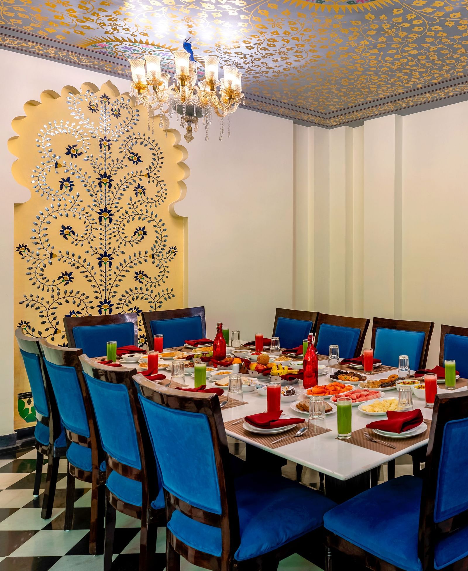 Elegant dining setup with blue chairs and Rajasthani wall motifs