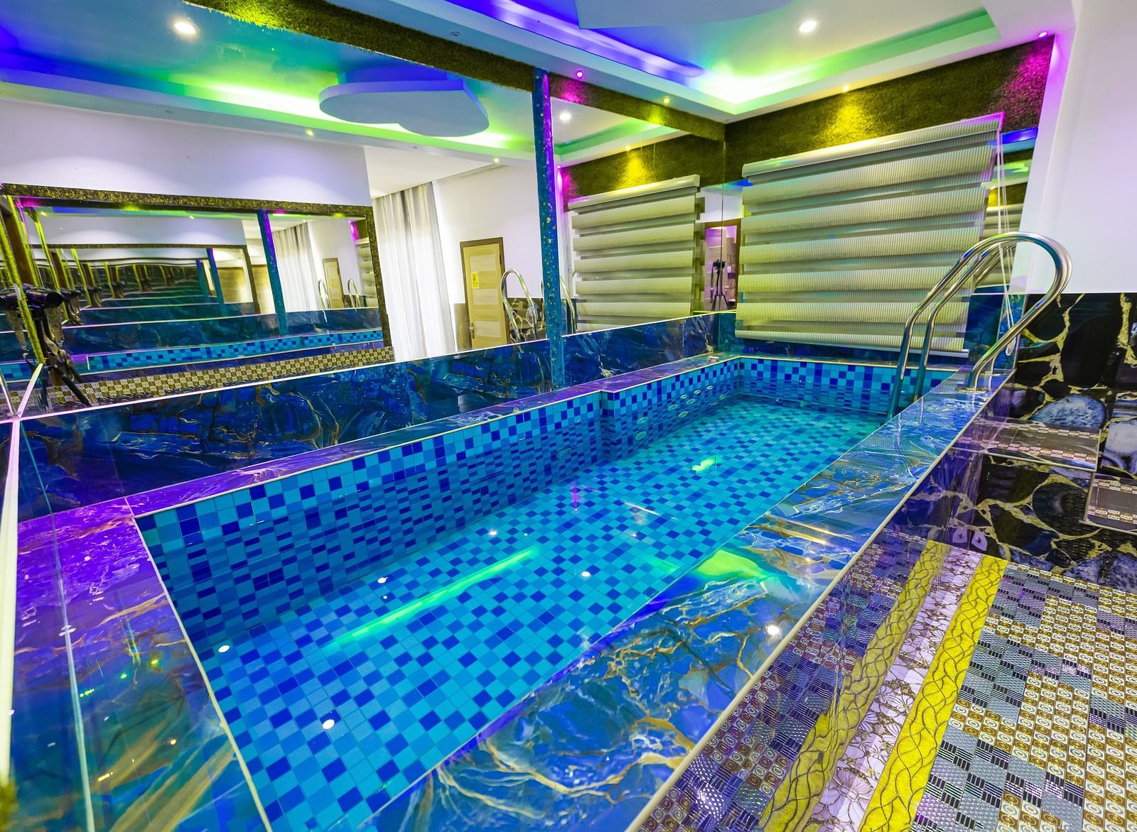 a mini swimming pool surrounded by mirrors on walls on all sides and the entire area is illuminated with different colours of lights - Parakkat Nature Hotels and Resorts, Munnar