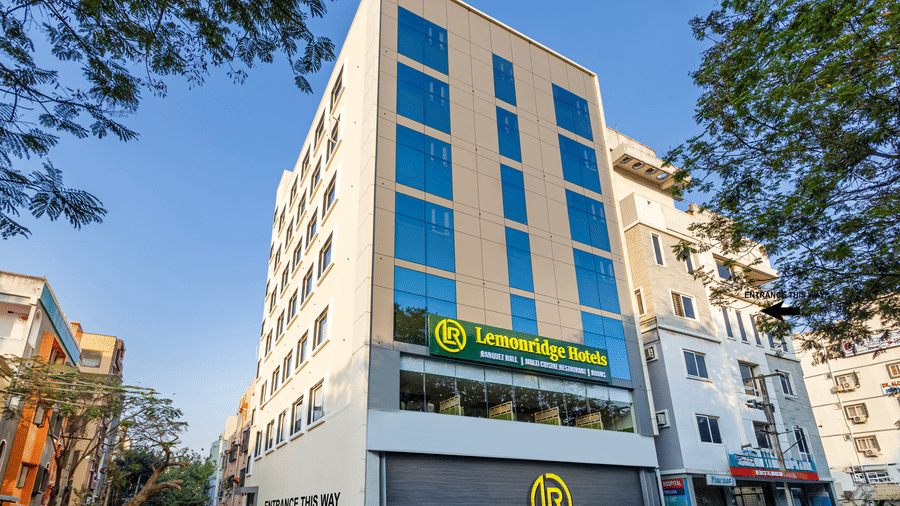 Facade of Lemonridge by Monday Hotels - KPHB featuring a modern multi-story white exterior with blue glass windows, prominent branding signage, and a front staircase entryway.