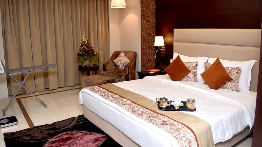 A comfortable bed with pillows and a patterned runner is seen in a room at Lords Plaza Surat.