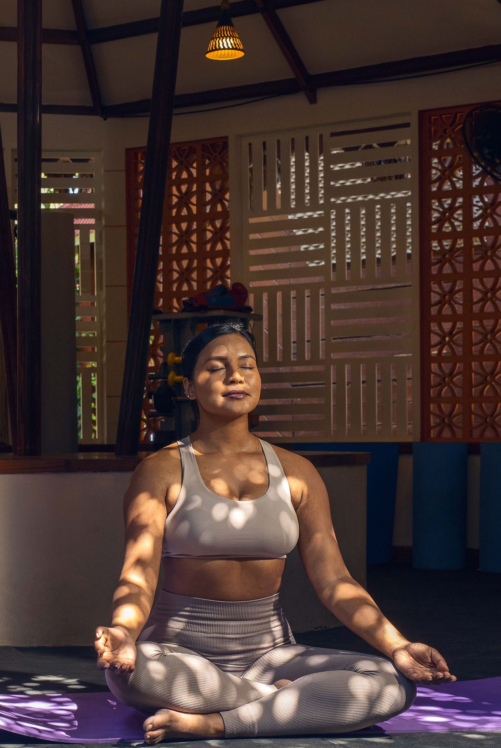 : A sign for the  Opal Fitness Center displayed alongside a statue of a person in a meditative pose. The background includes rustic wooden elements and a calm environment - Coral Reef Resort & Spa, Havelock