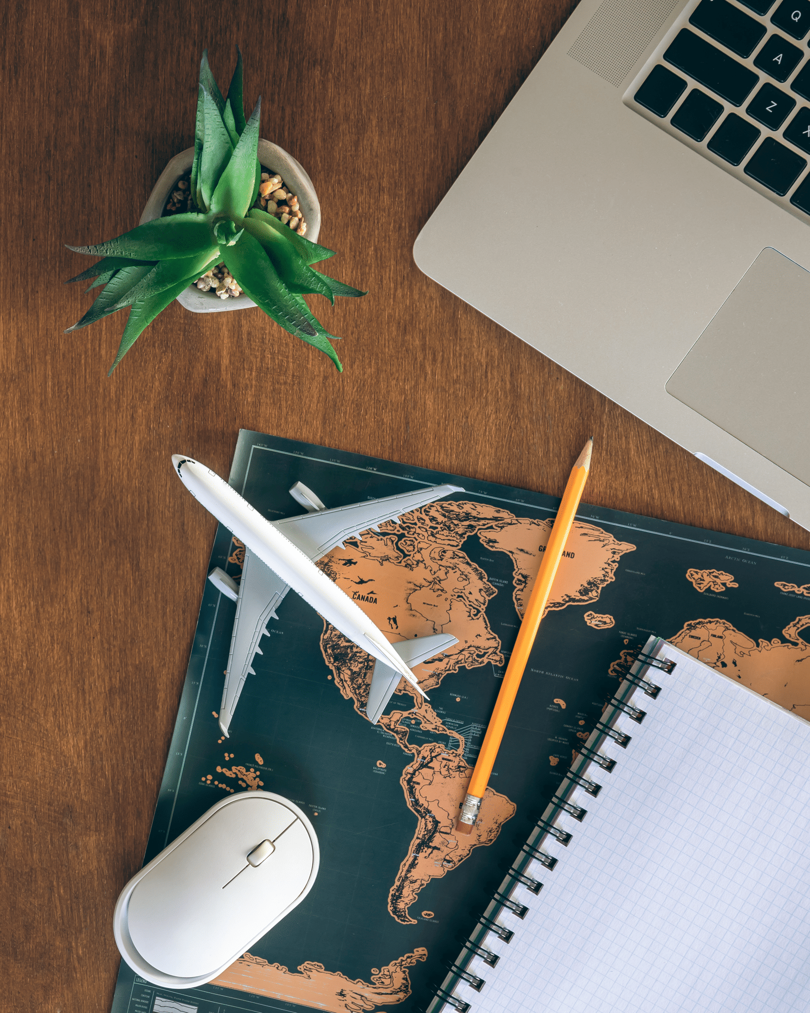 airplane-miniature-notepad-world-map-laptop-wooden-table