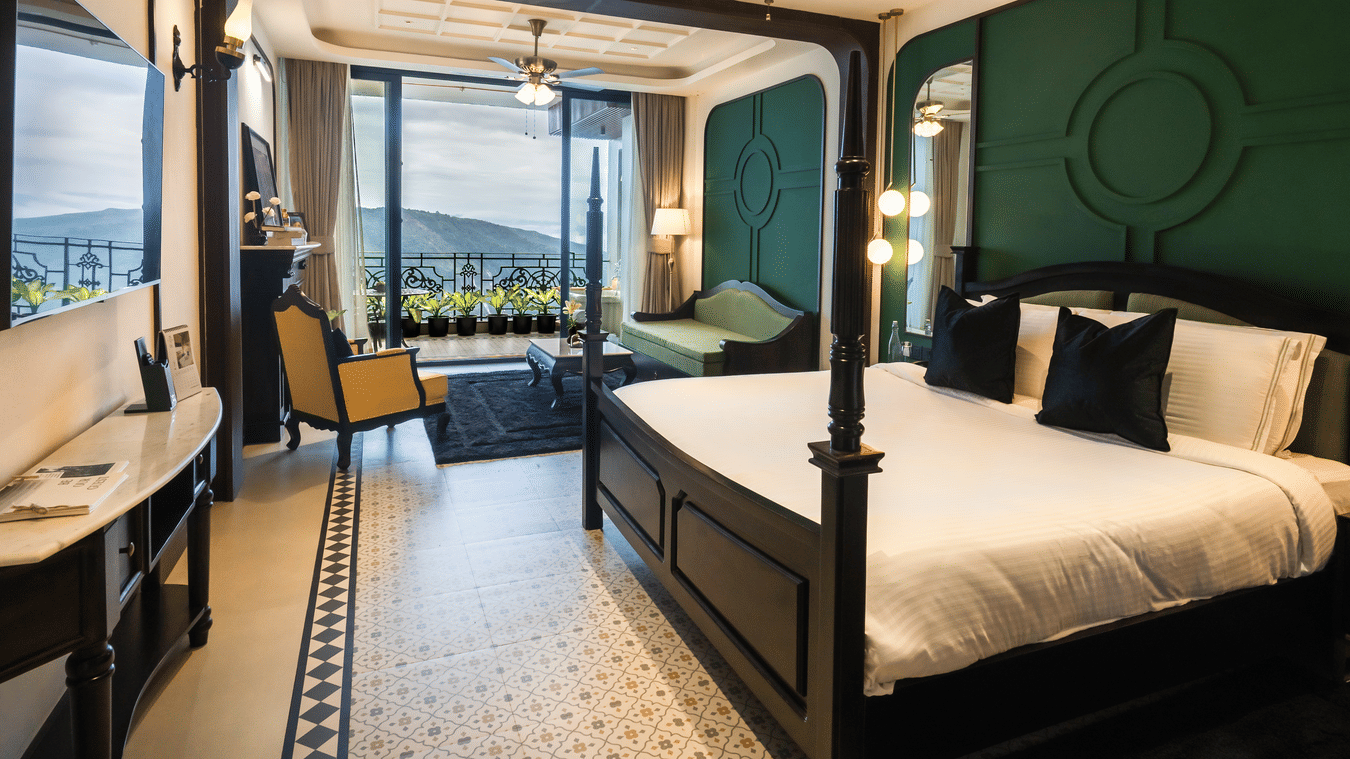 Bedroom with king size bed, flat TV screen, chair, sofa, and a view of the balcony - Polo Cherrapunjee Resort - Best Resorts Meghalaya