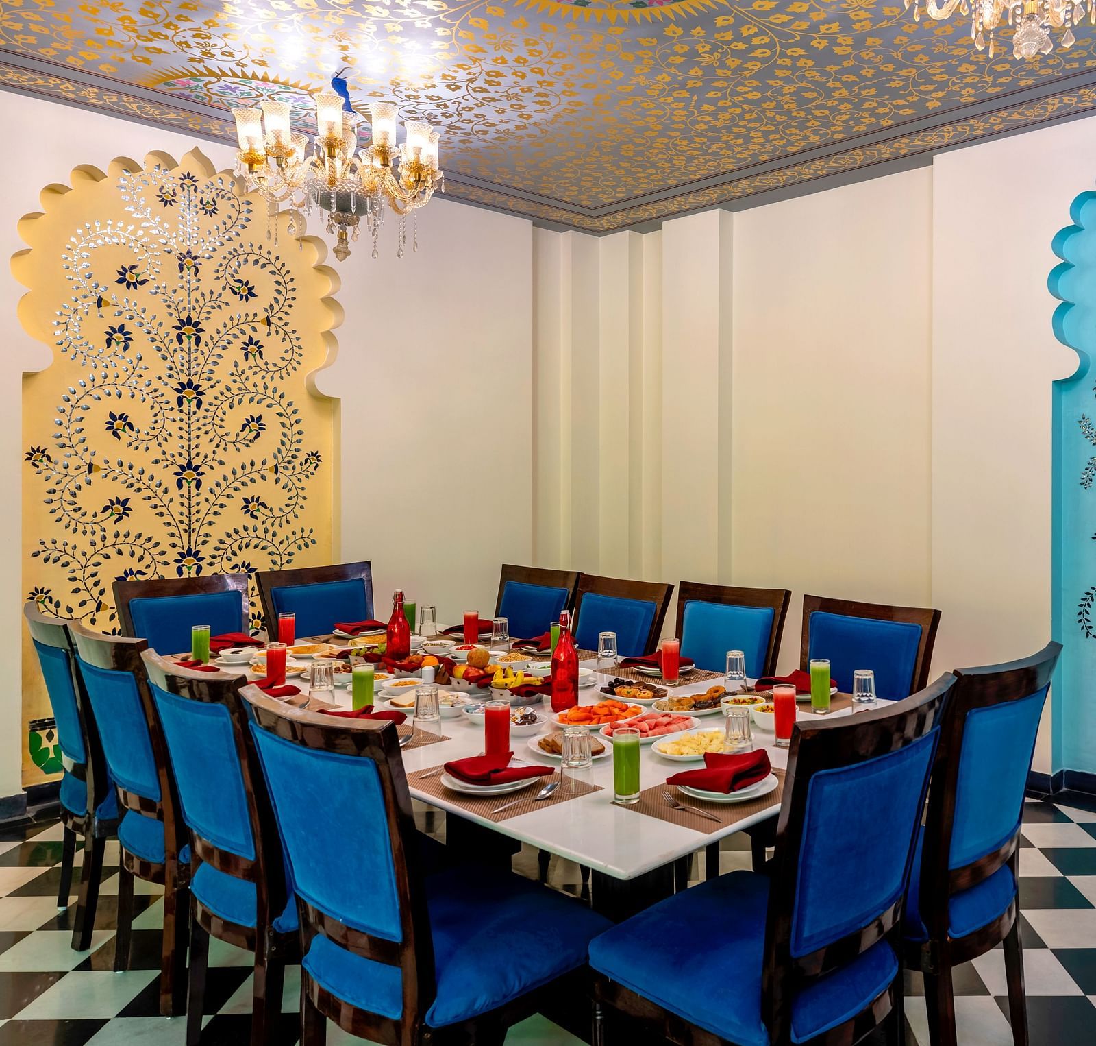 Elegant dining setup with blue chairs and Rajasthani wall motifs