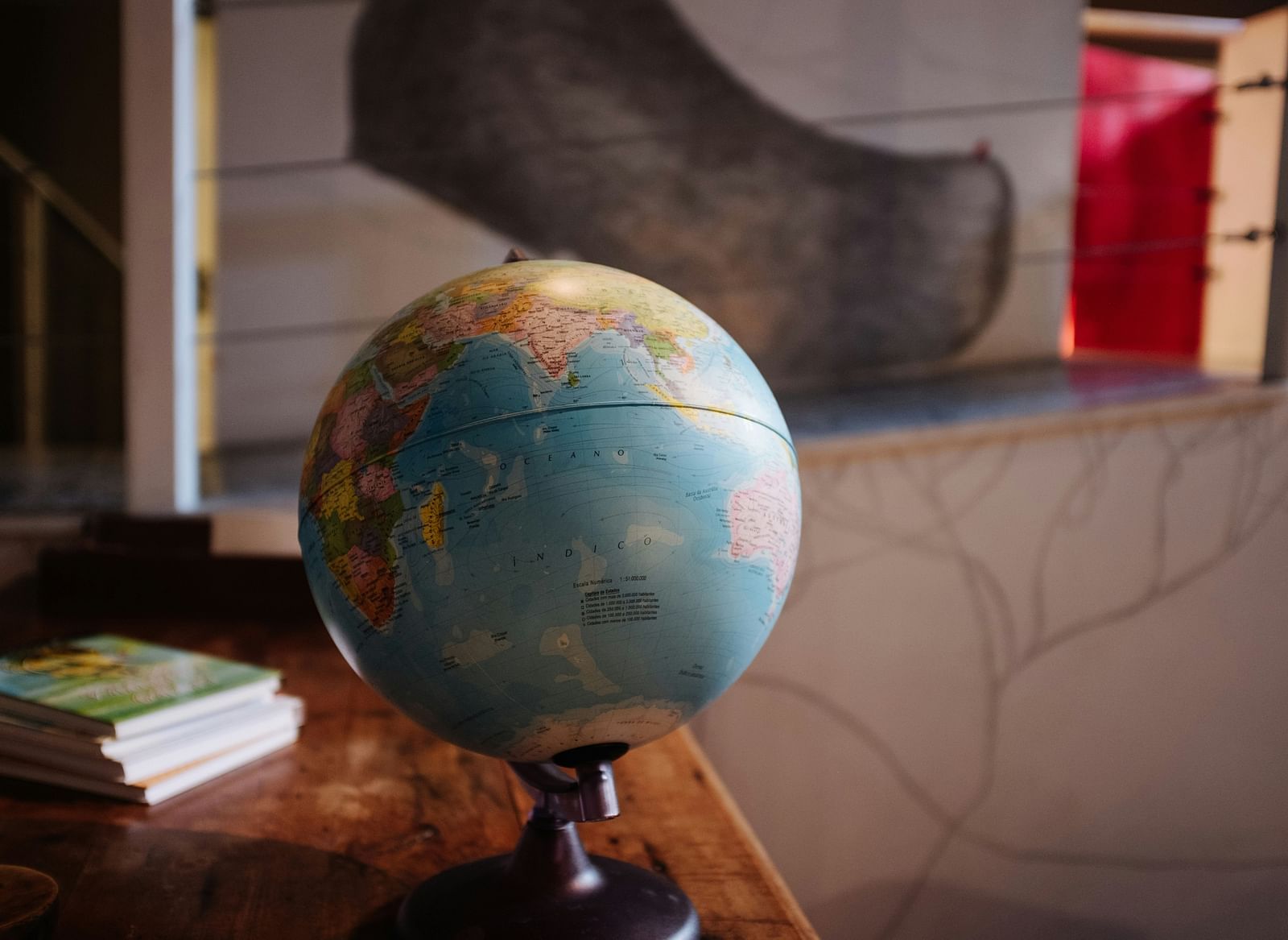 A globe kept on a table with books behind it.