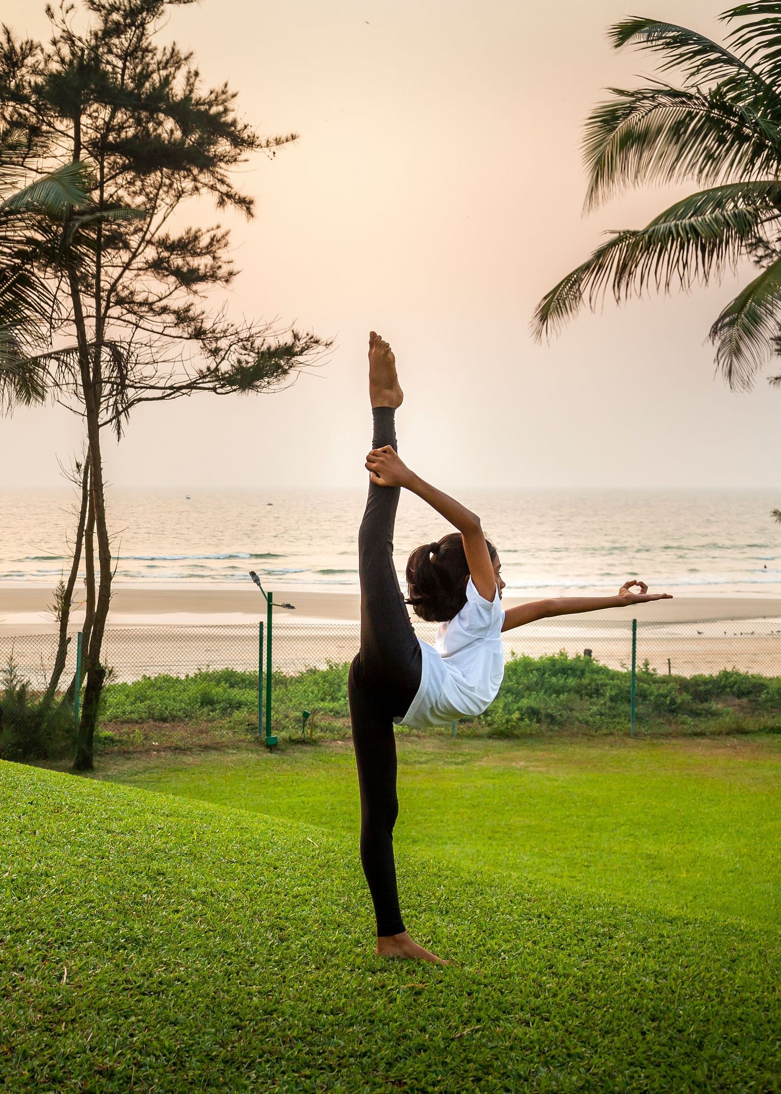 a person doing an asana on the lawn - Caravela Beach Resort Goa