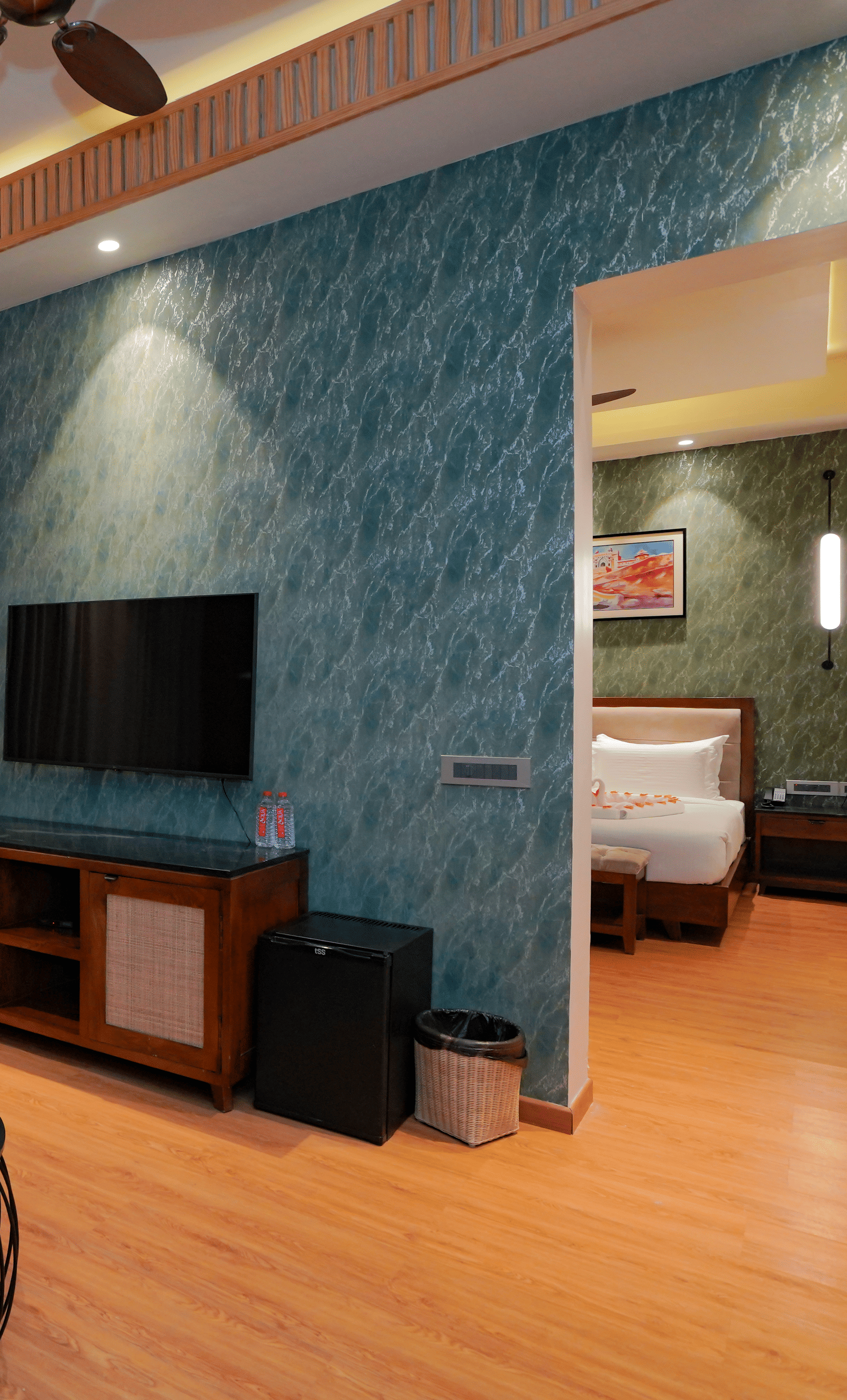A spacious hotel suite with a living area, separated from the bedroom by a partition wall.