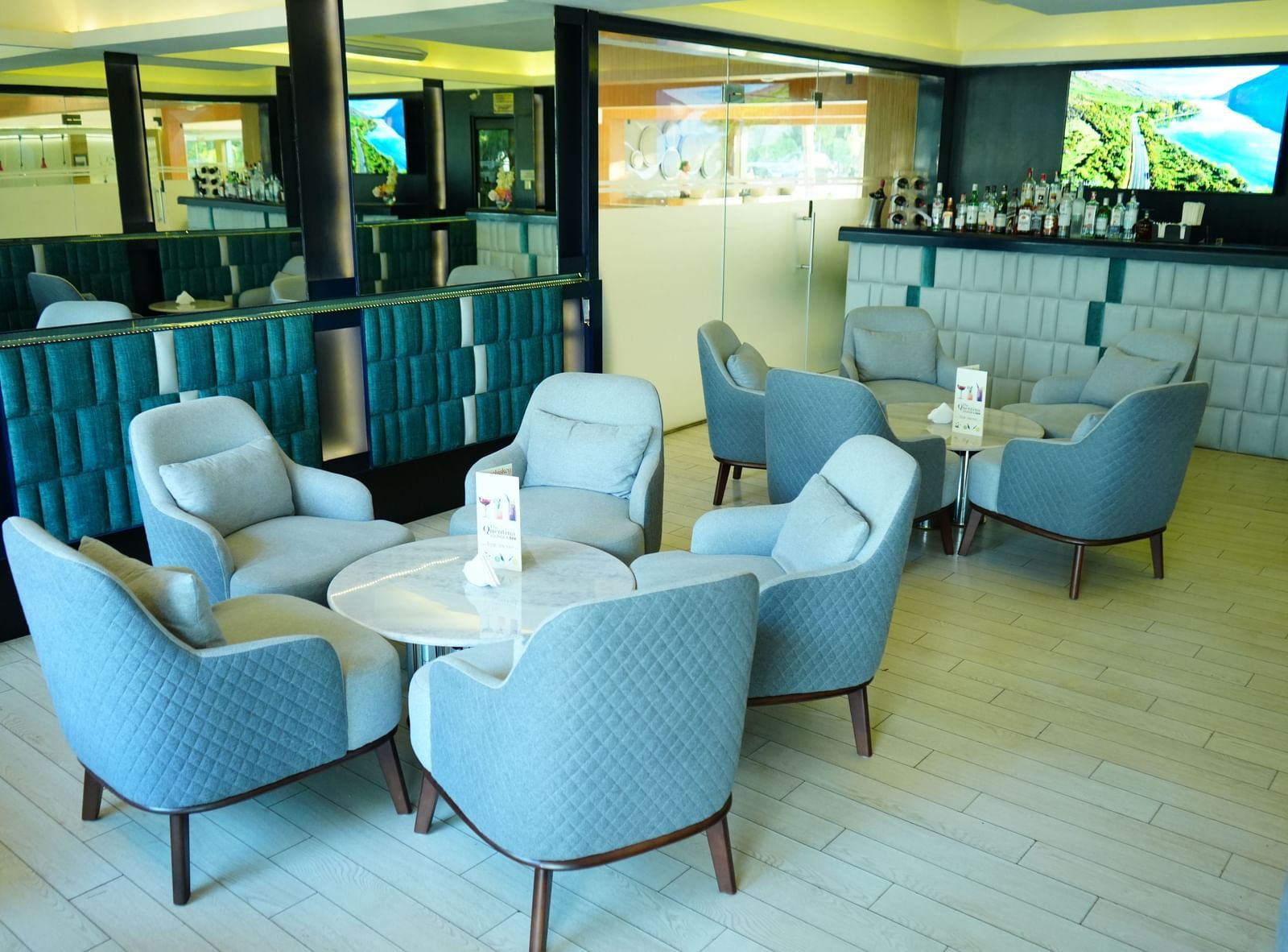 Lounge seating with armchairs and tables beside large glass windows at Grande Bay Resort & Spa.