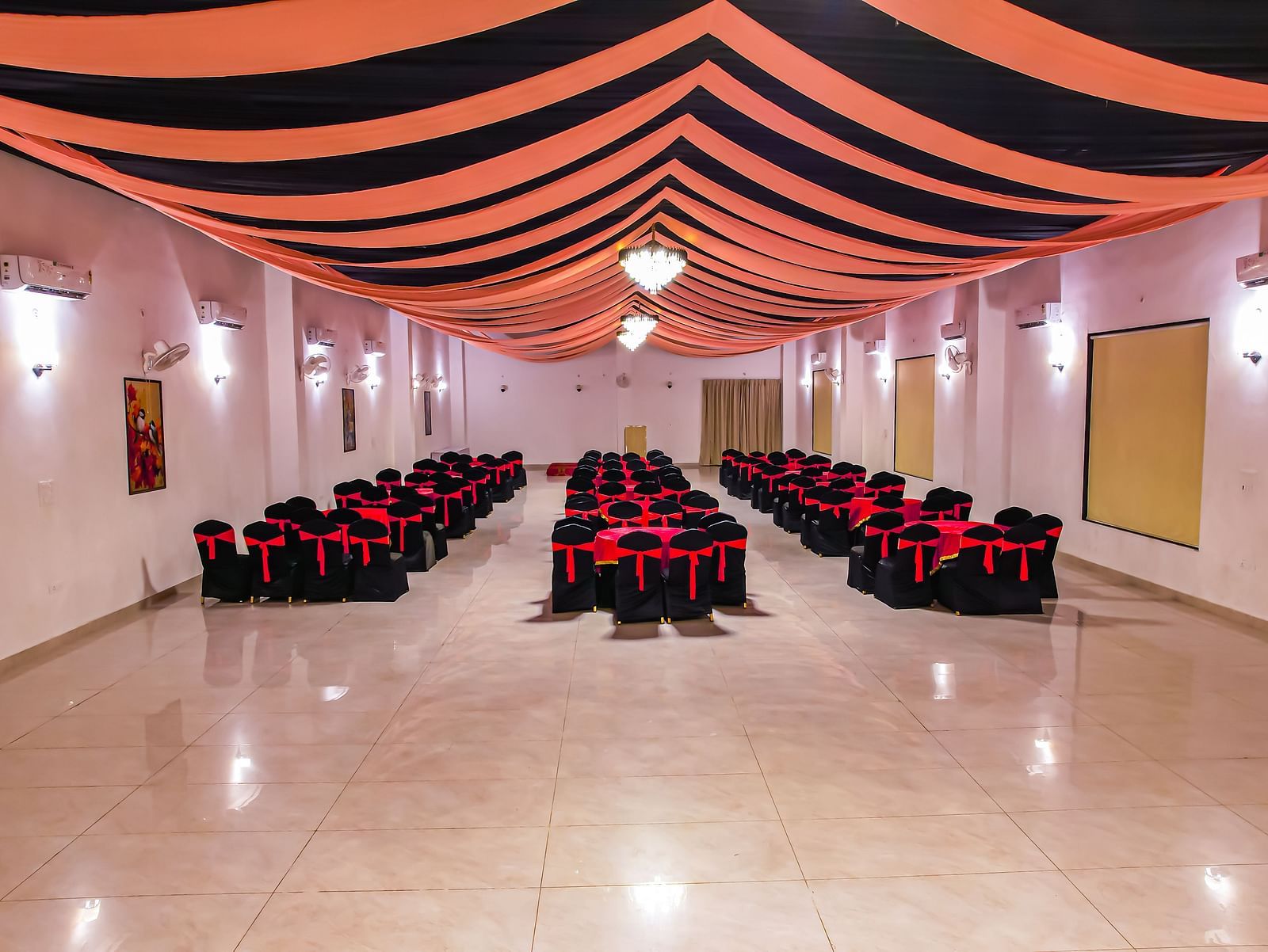An empty banquet hall at Vedikant Resorts The Mallard Corbett has rows of chairs set up for an event under a decorated ceiling.