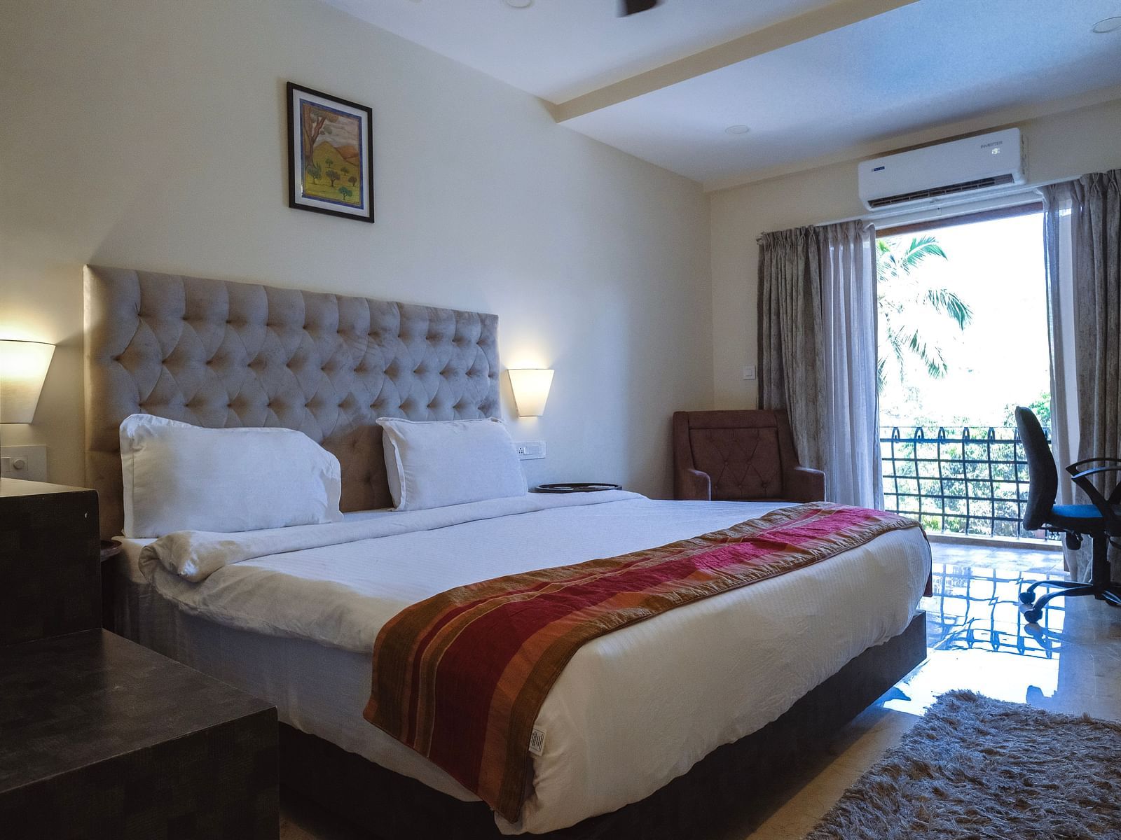 Spacious bedroom with a red runner on the bed, natural lighting, and balcony access at The Verda de Miranda Resort.