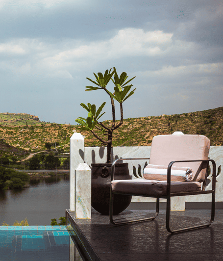 Infinity pool overlooking the lake and surrounding Aravalli hills with outdoor lounge seating | YAAN Udaipur