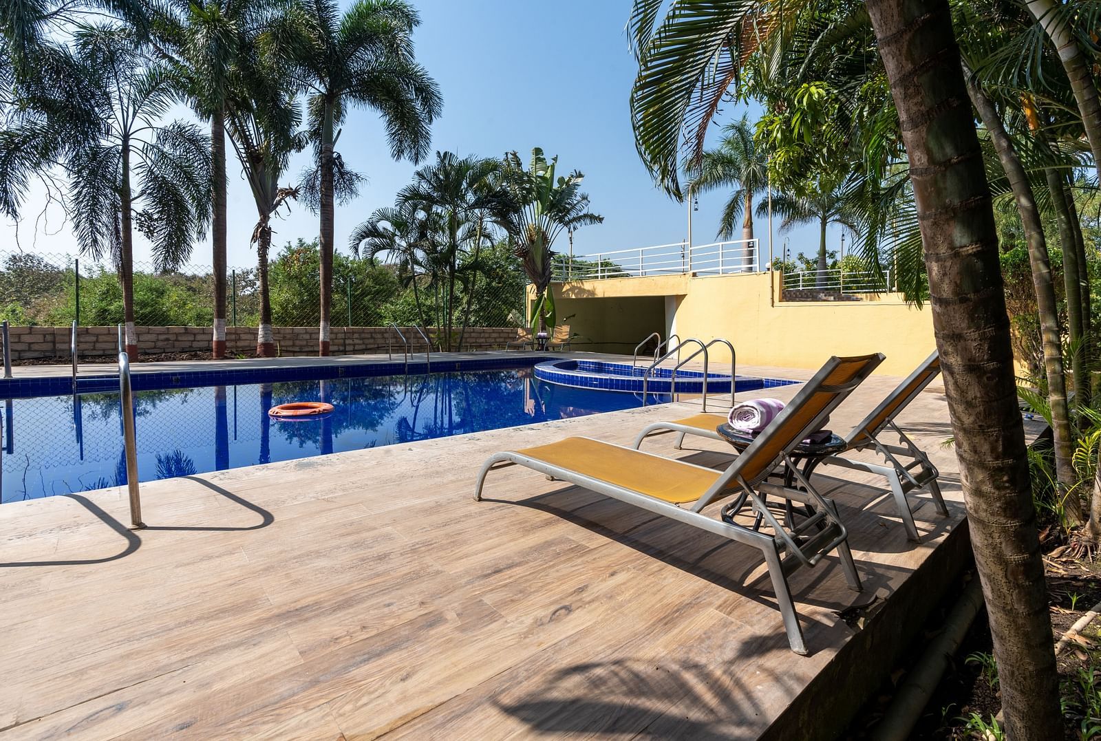 Diagonal view of the swimming pool, with poolside chairs and trees around the area.