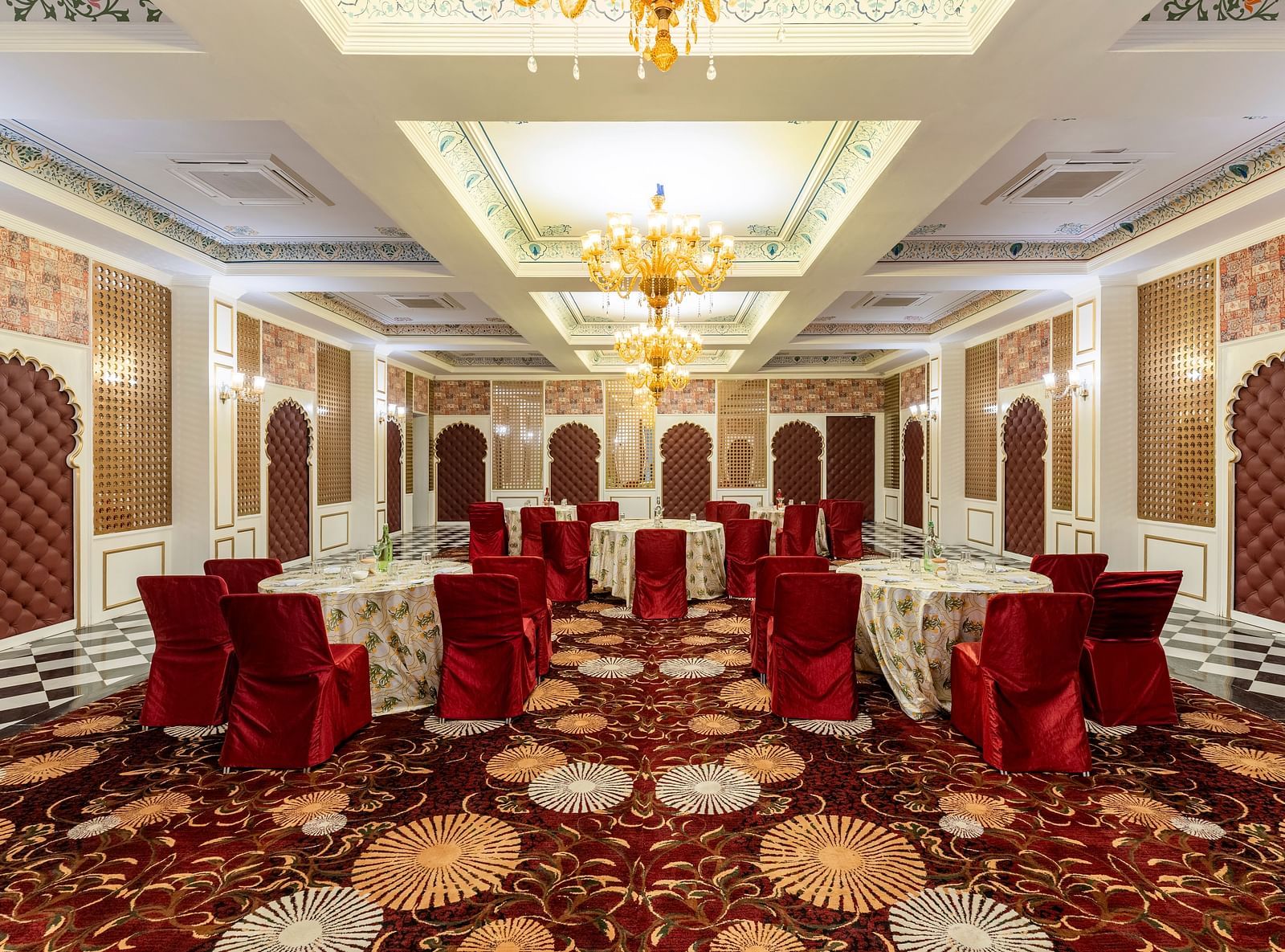 Luxurious banquet hall with red chairs and ornate ceiling at Kesar Bagh Palace.