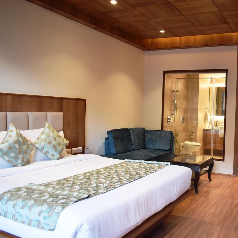 Hotel bedroom with modern furnishings and a cosy sofa in the corner at The Orchid Hotel, Manali
