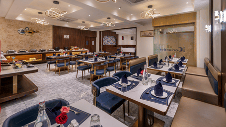 Neatly laid dining tables fill a contemporary restaurant with stylish light fixtures - Lords Inn Sangam, Bhopal