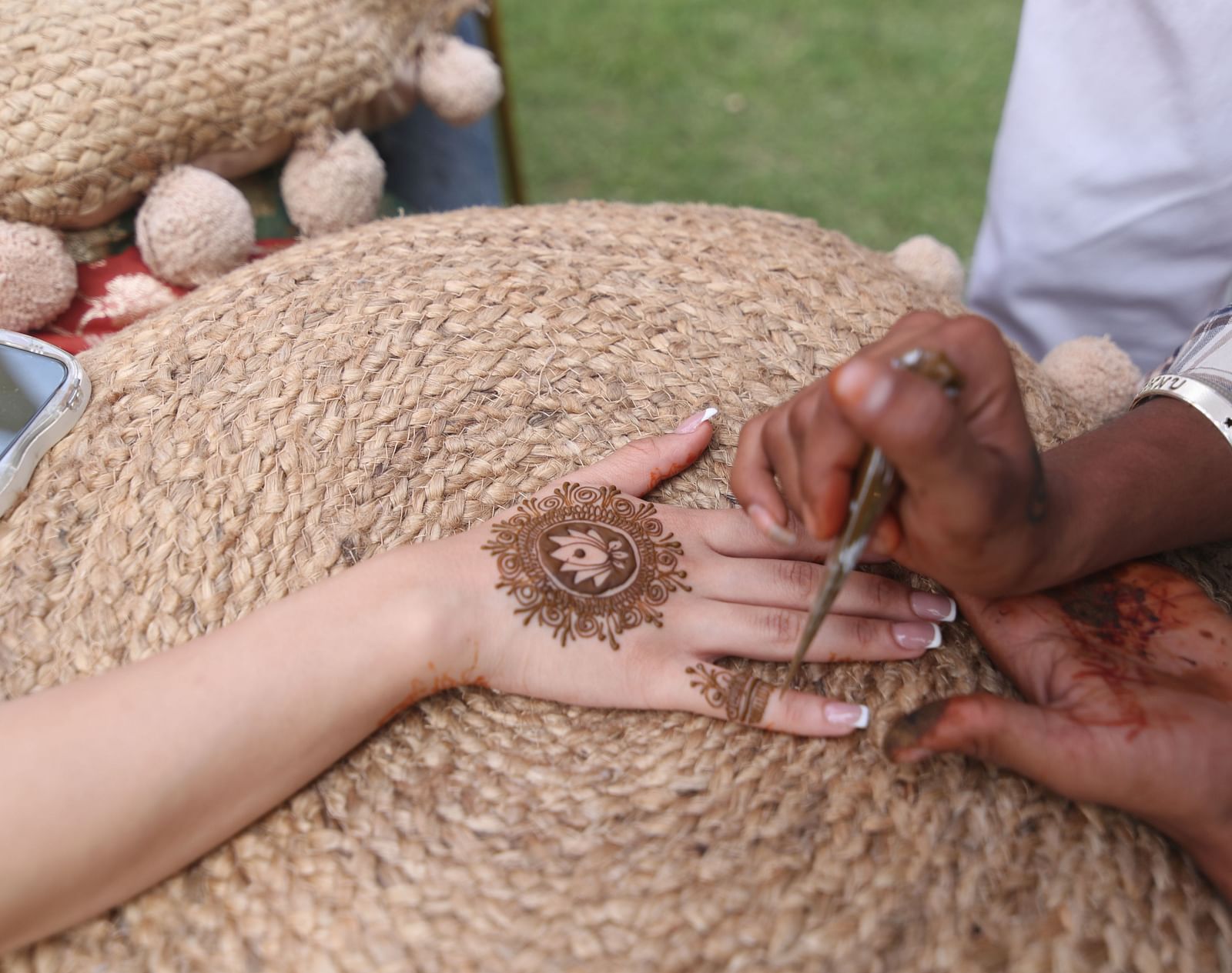 Close-up of applying mehendi on hand during a traditional ceremony at Tisya Farms, Gurgaon.