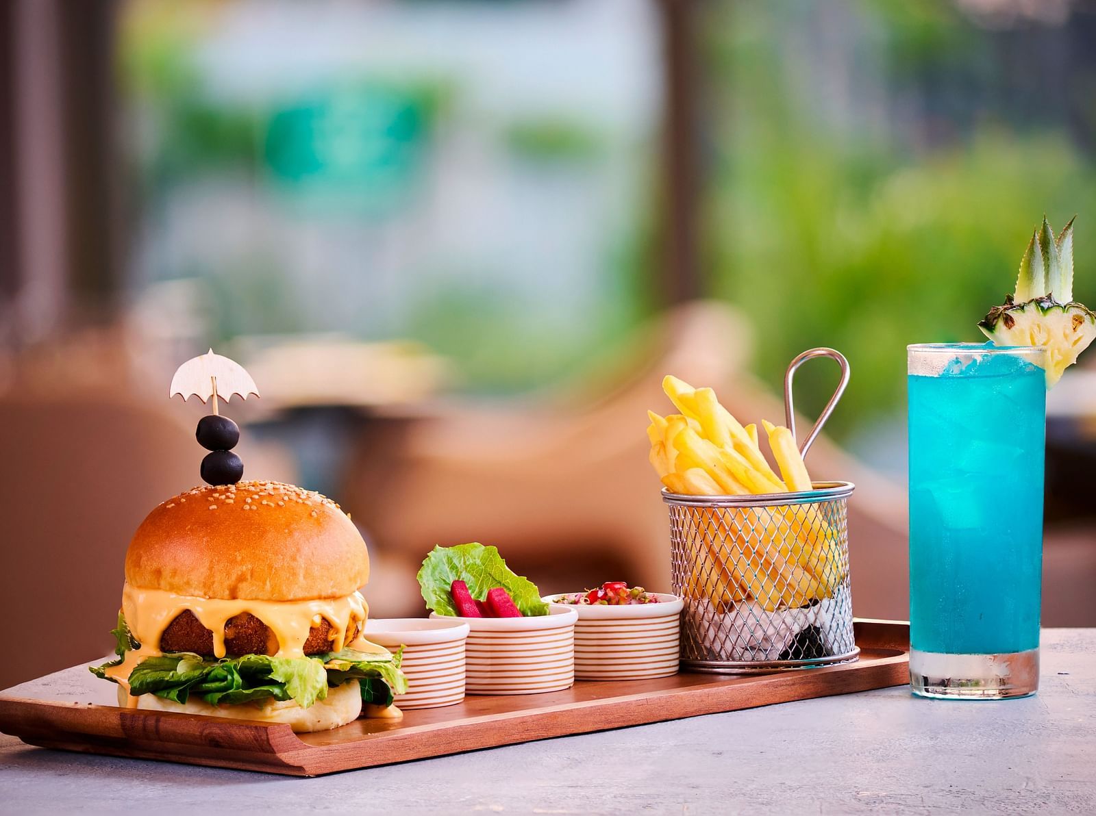 A meal of french fries and burger placed next to a blue drink.