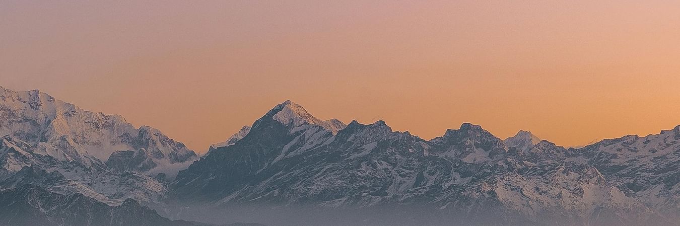 Mountain silhouette at dawn with layered hills in misty morning light creating dramatic Himalayan landscape