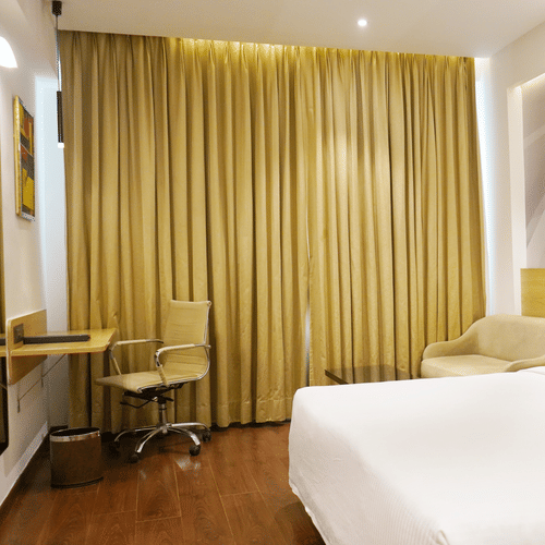 An image of a bedroom featuring a double size bed, flat TV screen, work and desk,  and other items - Nemsia