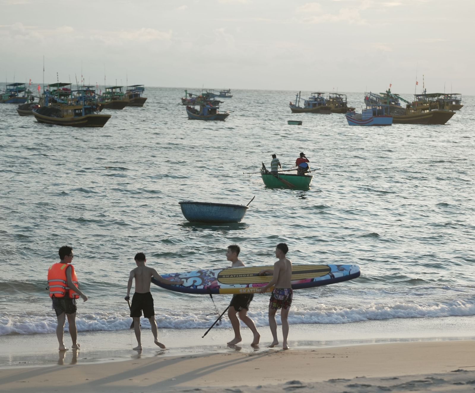 People engaging in water activities such as paddleboarding and kayaking on the beach at WoCAL Retreat Ke Ga.