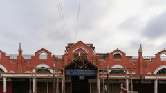 New Market in Kolkata with a person walking in front of it and numerous other people sleeping in front of it