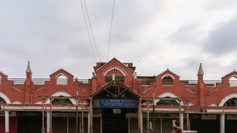 New Market in Kolkata with a person walking in front of it and numerous other people sleeping in front of it