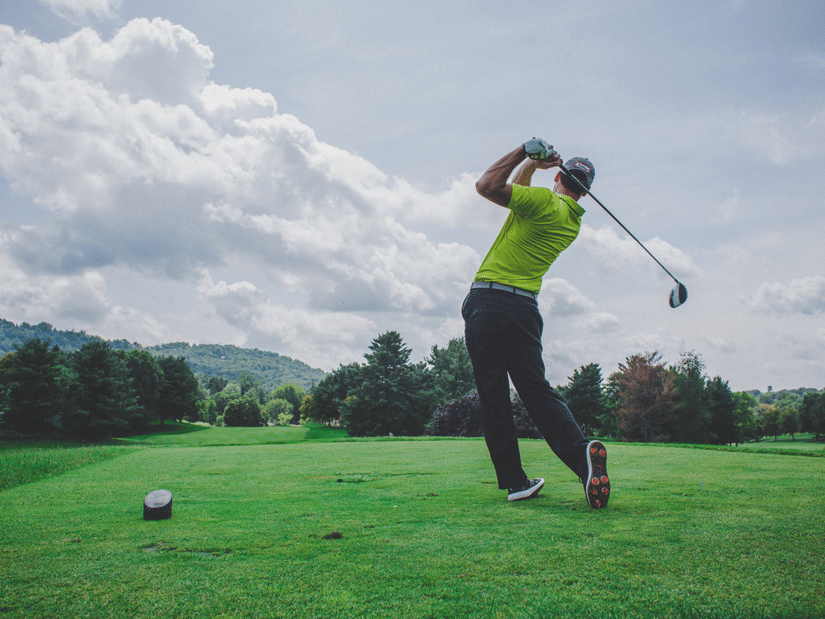 A view of a golfer after the swing, looking at the ball flying in the golf course filled with trees, one of the Chikmagalur packages at The Serai