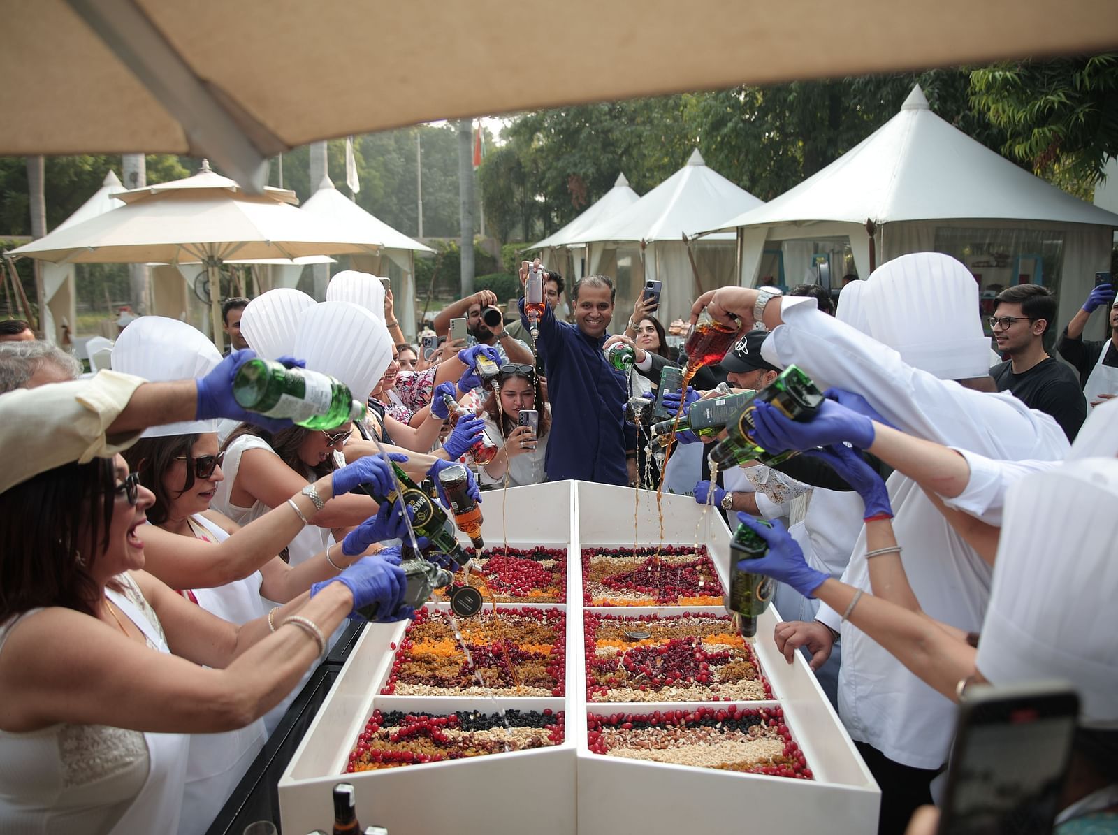Image of people preparing a Christmas cake, mixing dry fruits, in the open garden space at The Claridges New Delhi
