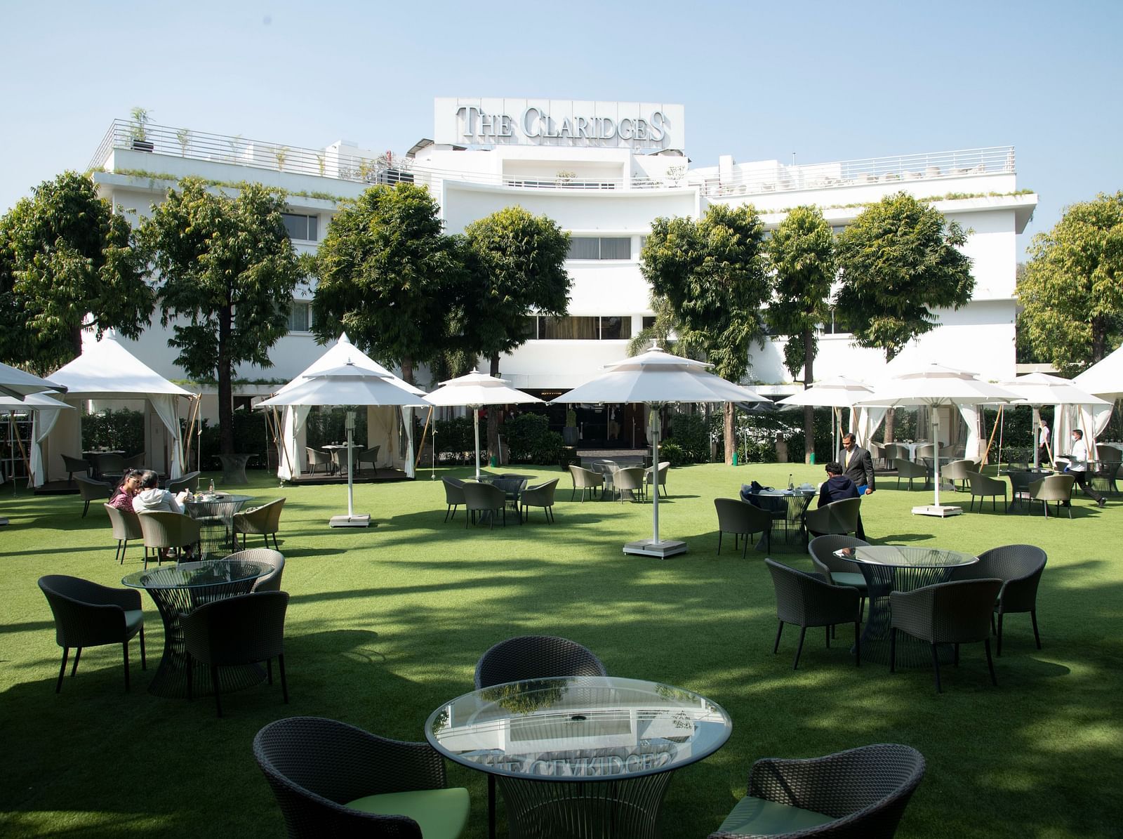 Beautiful landscape image of The Claridges Garden, featuring glass-top coffee tables scattered throughout