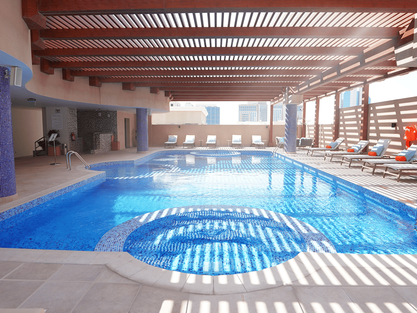 An overview of the swimming pool with sun's rays hitting the pool's surface - La Maison Hotel, Doha.