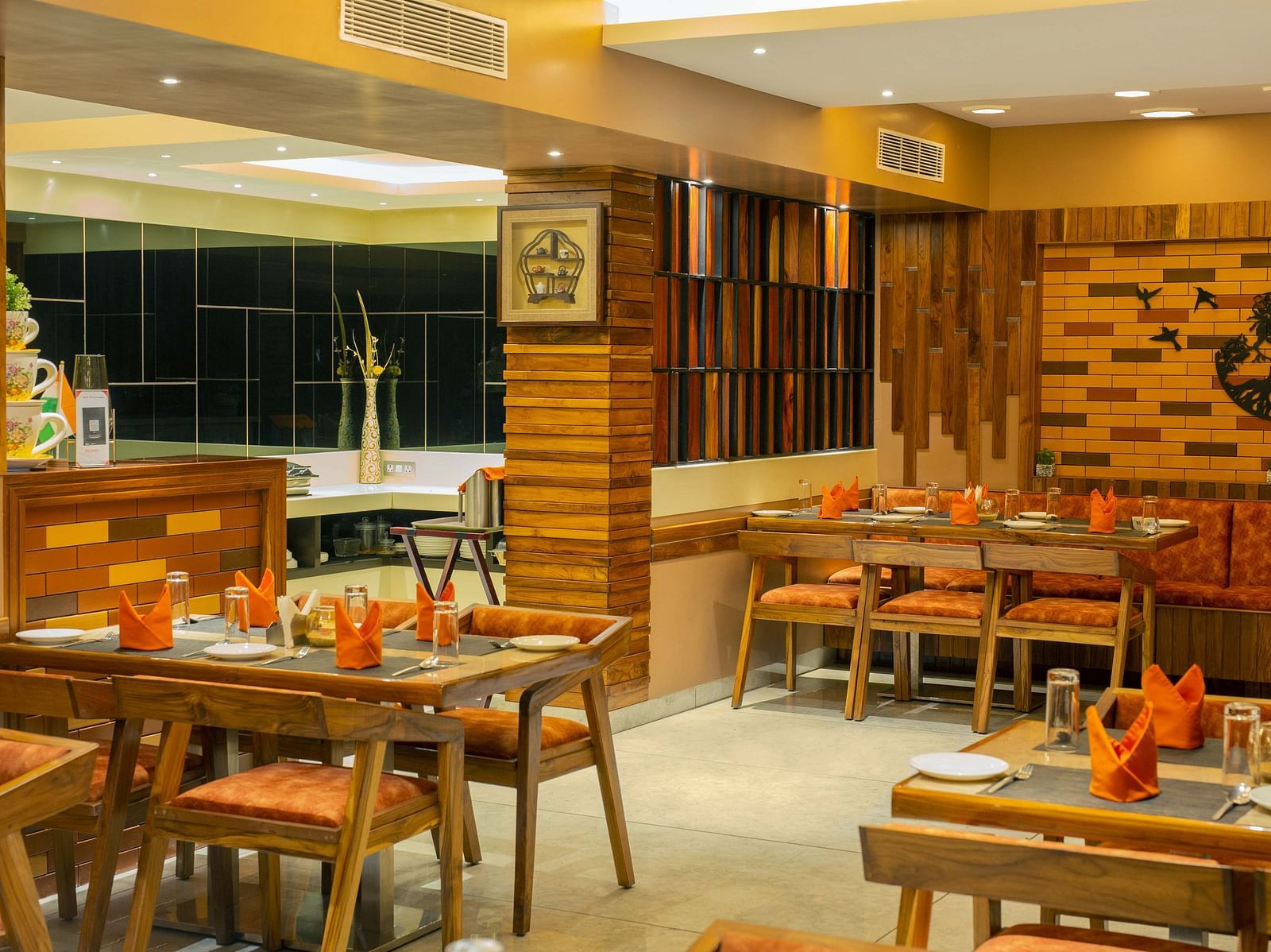 Image of the interiors of Honeycomb Restaurant at Coral Reef Hotel & Spa in Port Blair under warm lighting and walnut furniture 