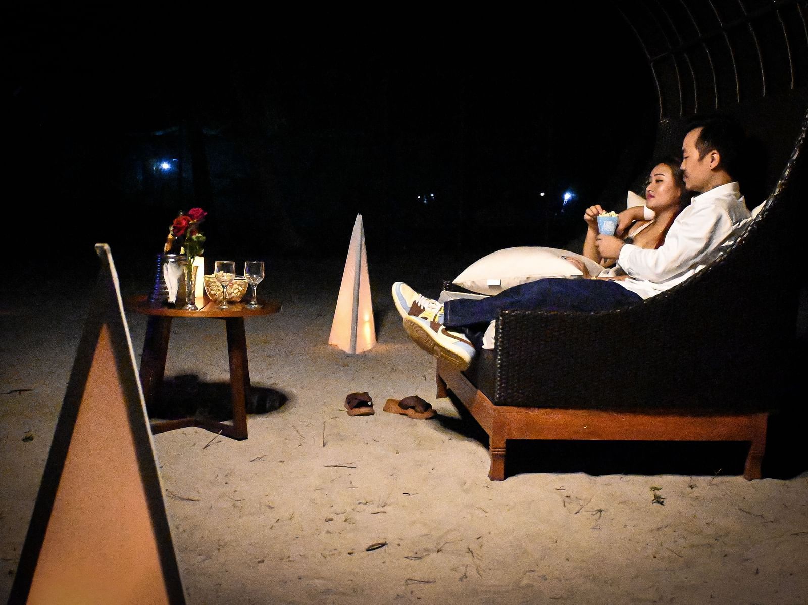 A couple sharing popcorn sitting in a couch setting with wine and roses in front of them - Coral Reef Resort & Spa, Havelock