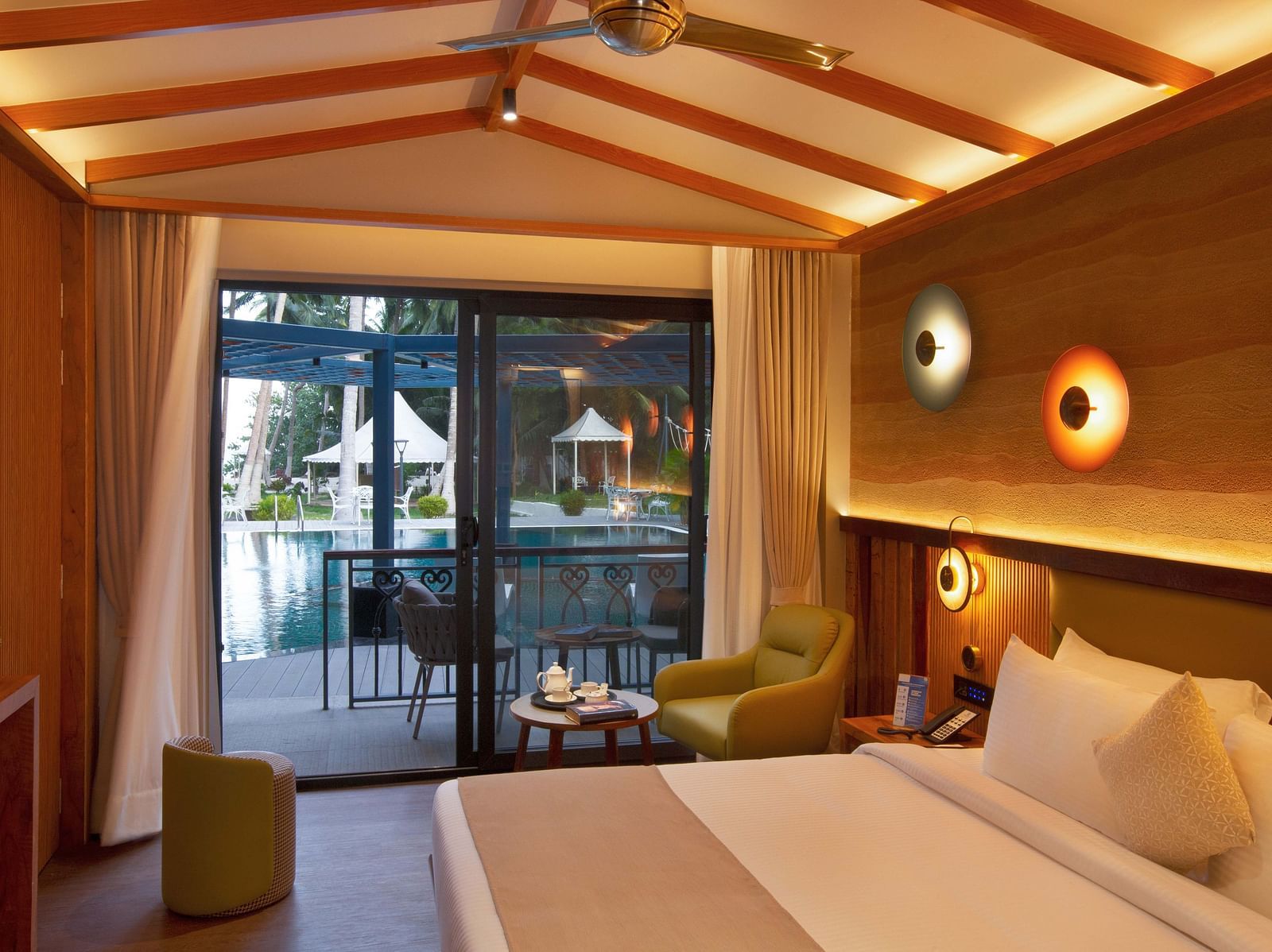 Coral Sapphire at Coral Reef Resort and Spa in Havelock featuring a plush bed and a seating space next to it with the door to the outdoor lounge area beside it  