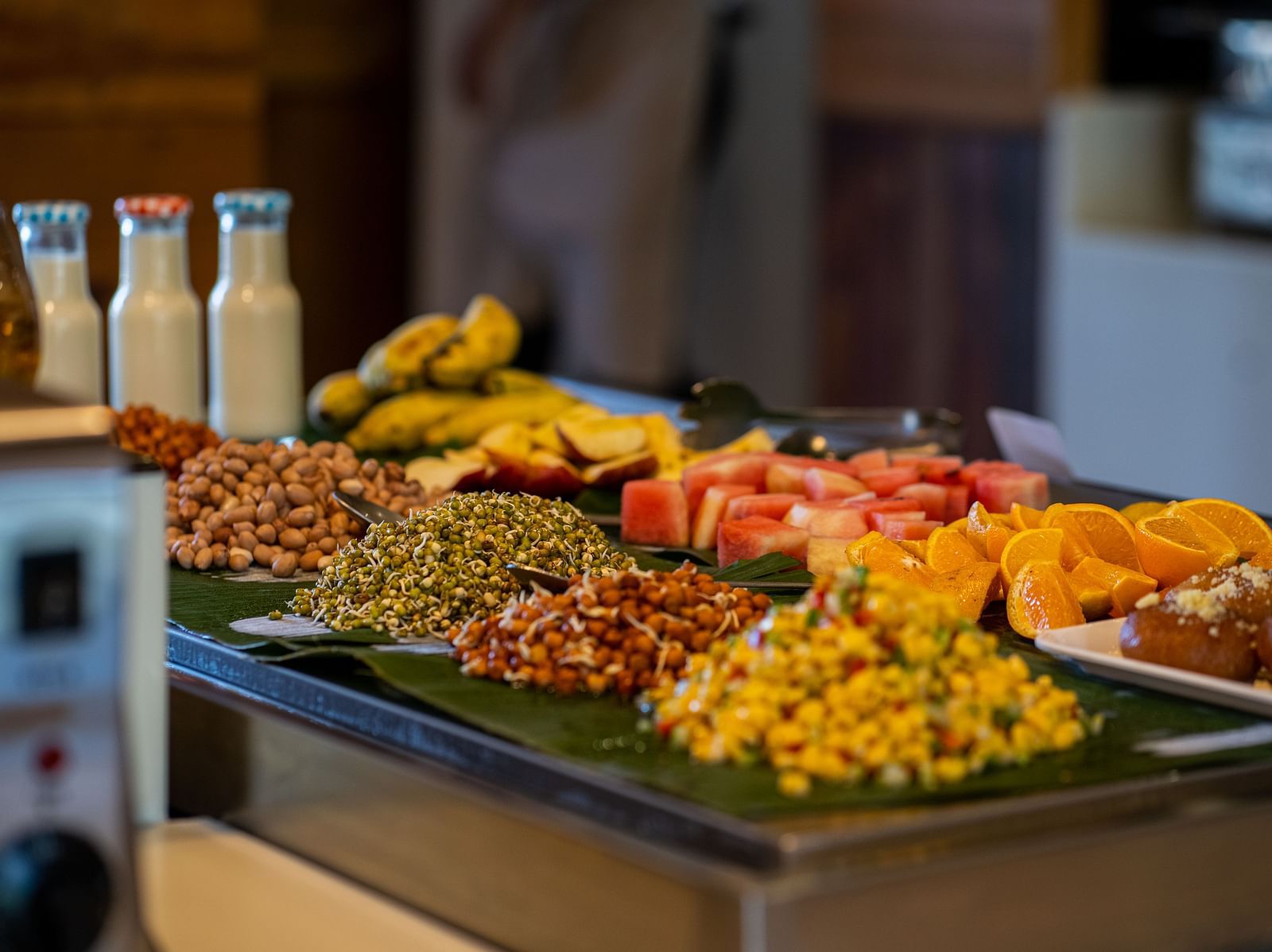 A detailed view of a buffet with assorted grains, legumes and fruits and a blurred background of the dining area - Coral Reef Resort & Spa, Havelock