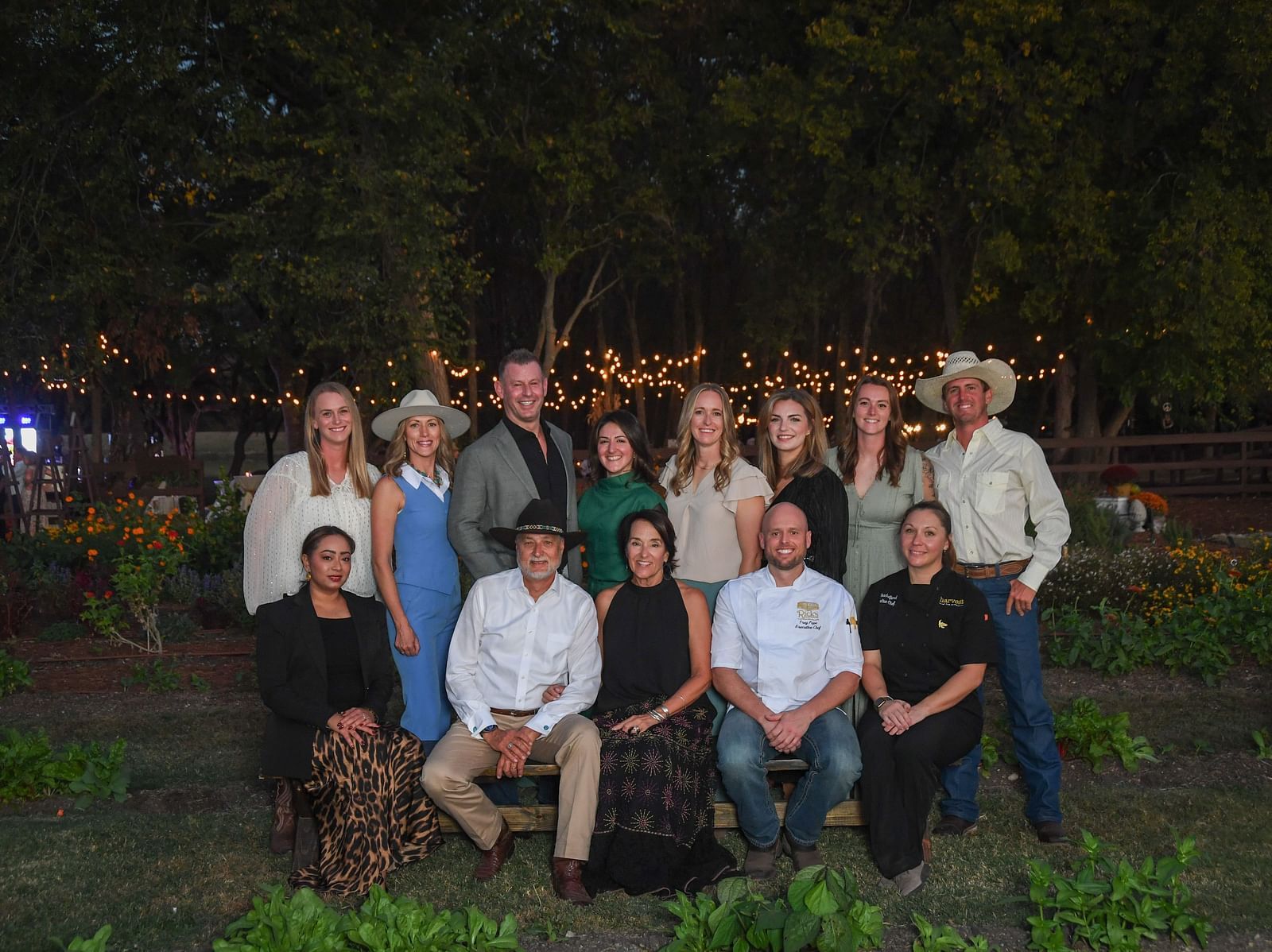 Group of people posing outdoors in a garden at night at The Grand Hotel & Ballroom, McKinney.