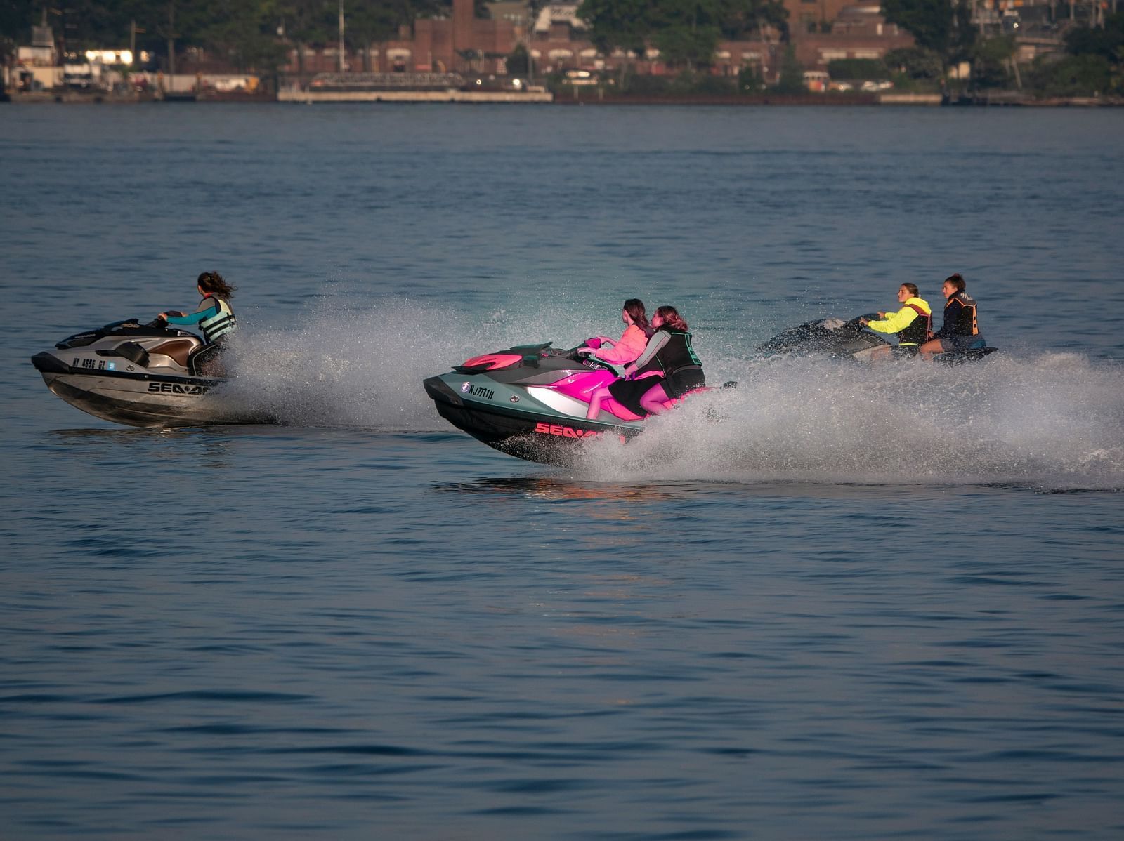 five people on three jet skis travelling on a waterbody as seen from afar.