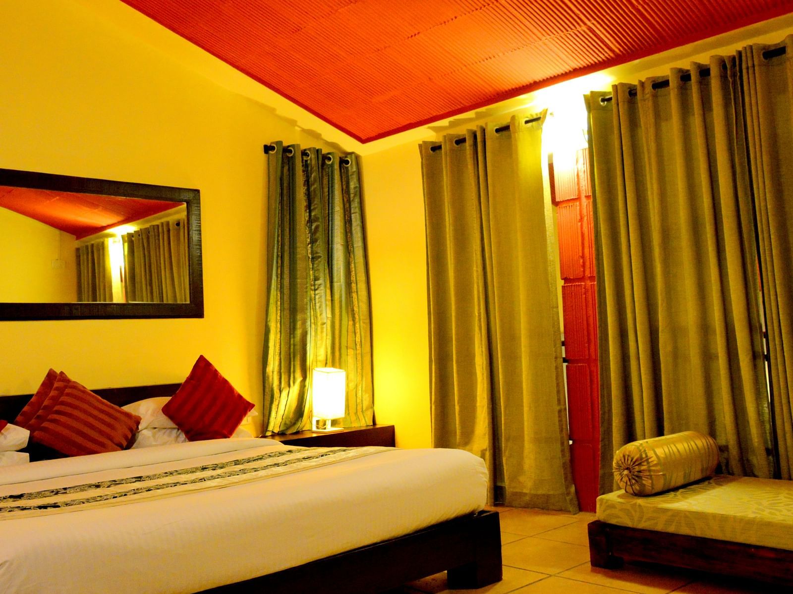 a bedroom with a bed and large curtains and a sofa on the side - Kadkani River Resort, Coorg