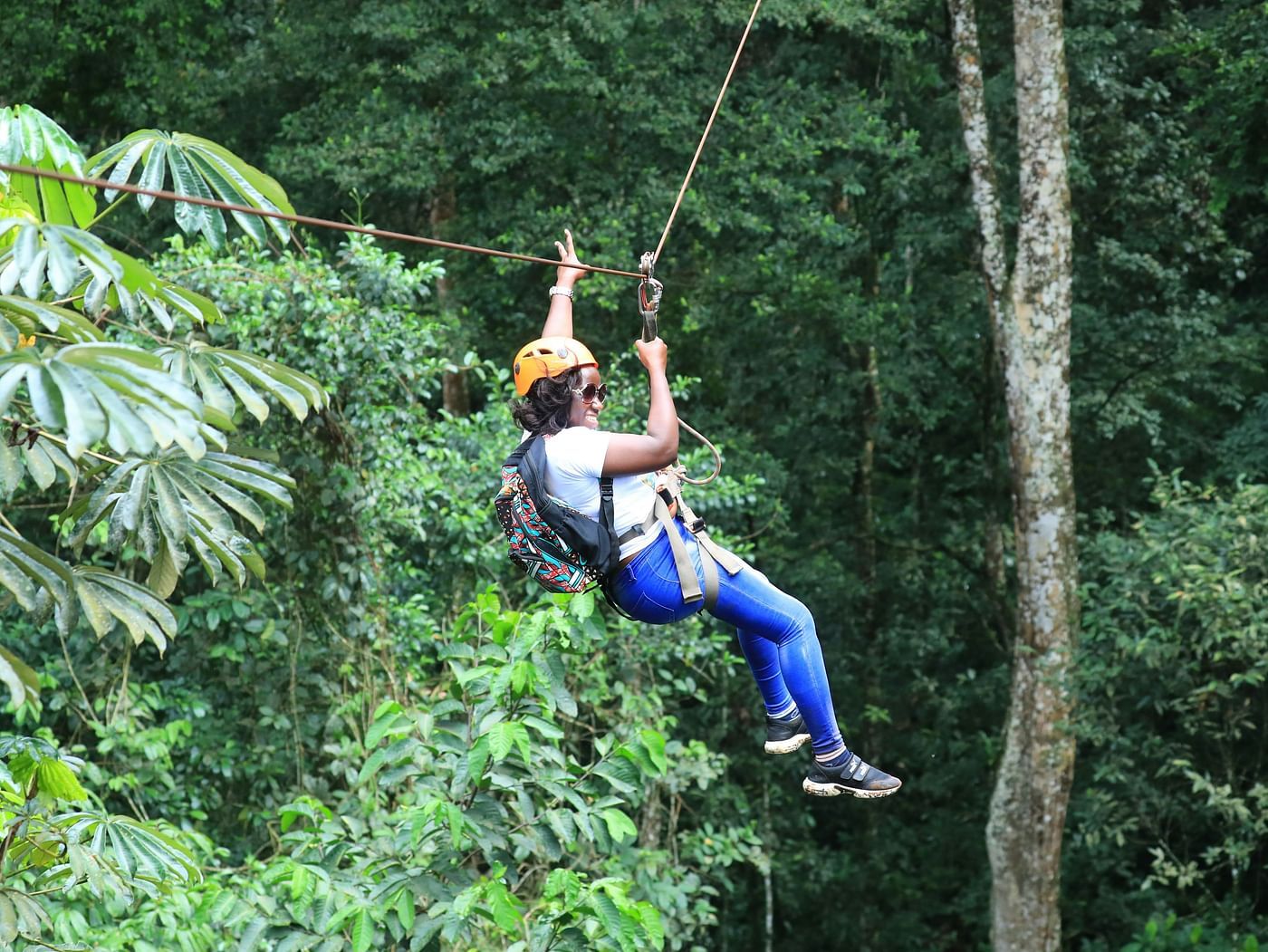 Image of a woman enjoying zip lining with a background of lush trees 