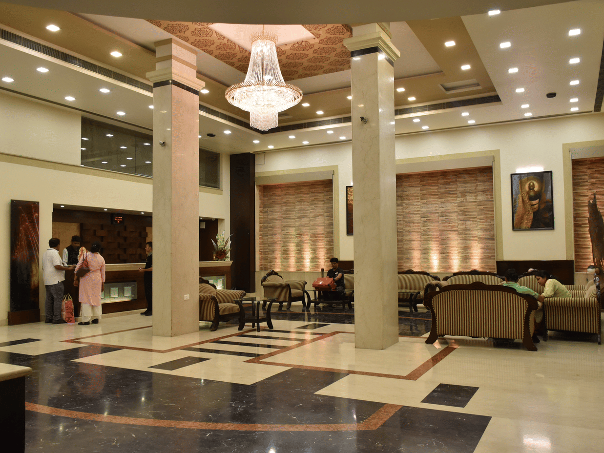 A wide angle view of the lobby with sofa sets, coffee tables and a chandelier on the top | Hotel City Inn, Varanasi
