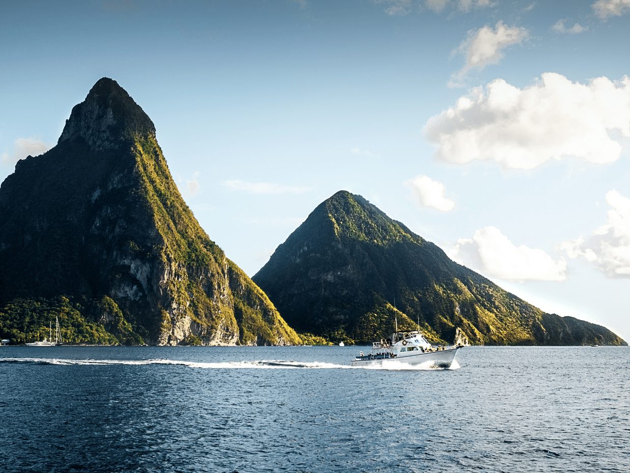 A view of two volcanic mountains and a cruise in the middle of the sea under a partly clouded sky.