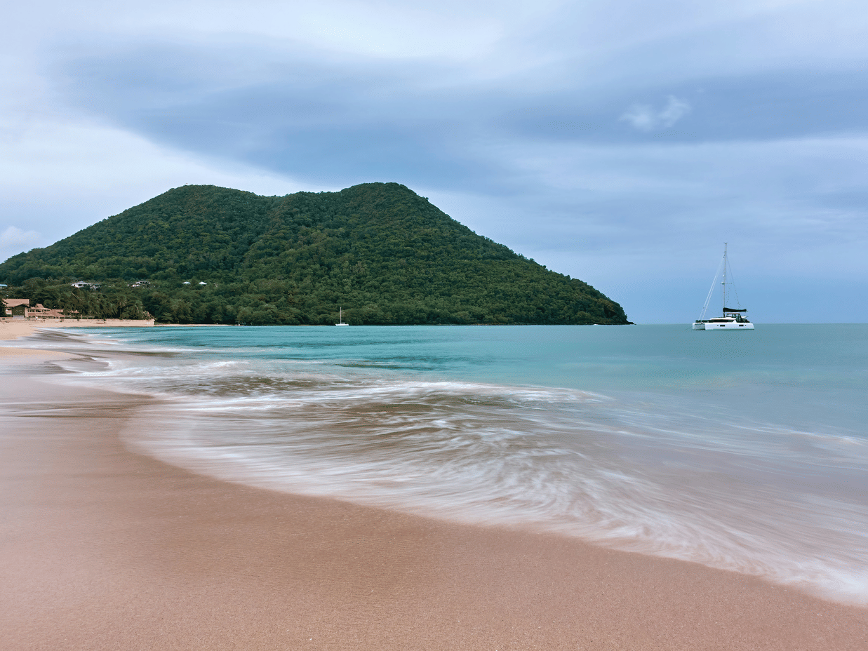 A tranquil sandy beach with gentle waves, turquoise waters, and lush tropical surroundings perfect for a relaxing escape.
