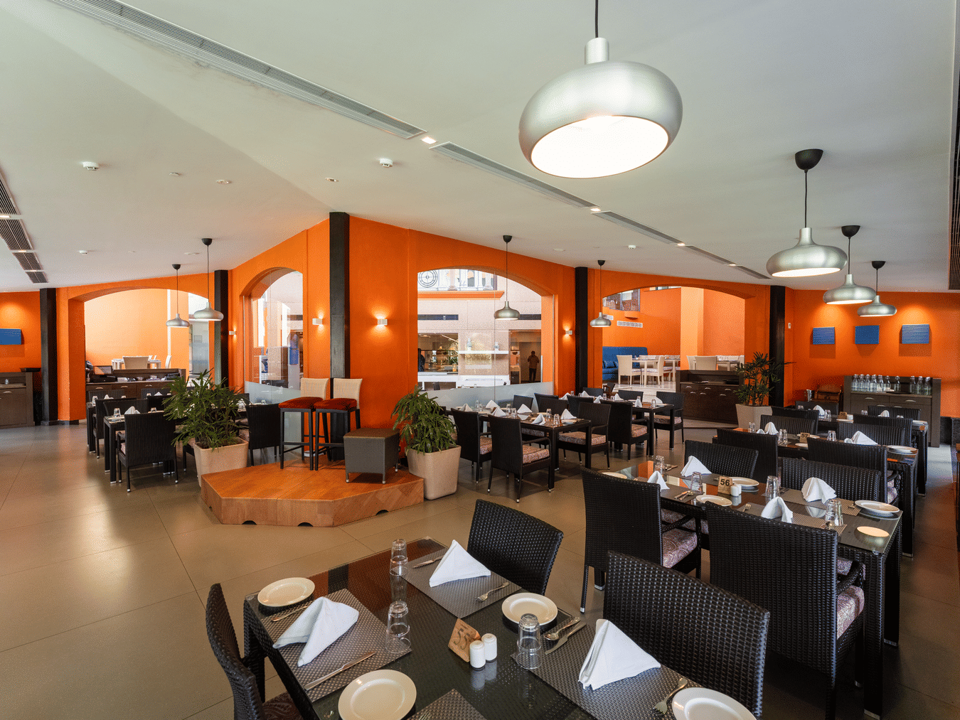 Modern restaurant dining area with orange feature arches at Kenilworth Resort & Spa, Goa.