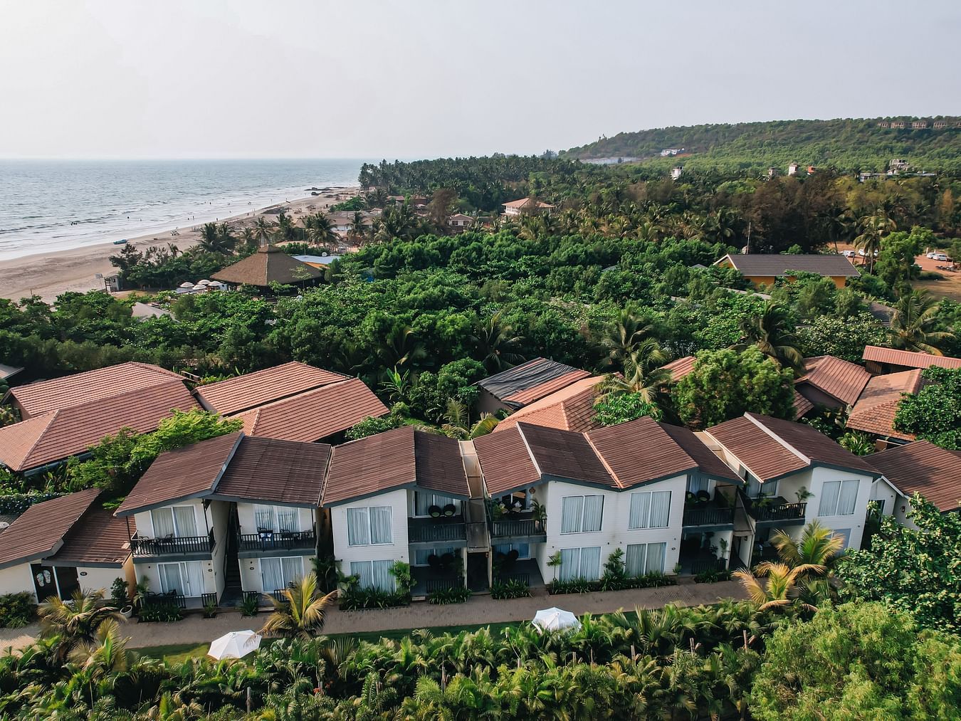 an aerial vie image of the facade of sibaya beach resort, morjim beach that is surrounded by lush tropical greenery