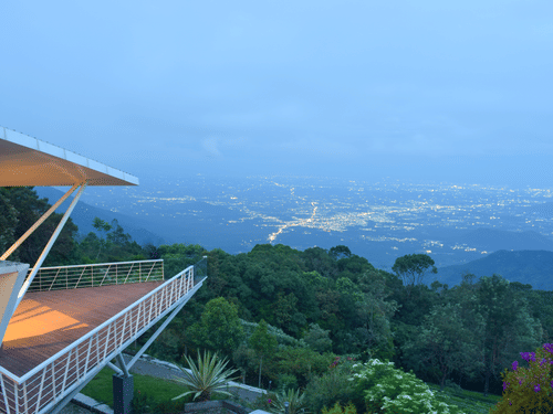 Twilight view of a balcony overlooking a lush valley and distant mountains at Ibex Resorts, Coonoor (Tapas).